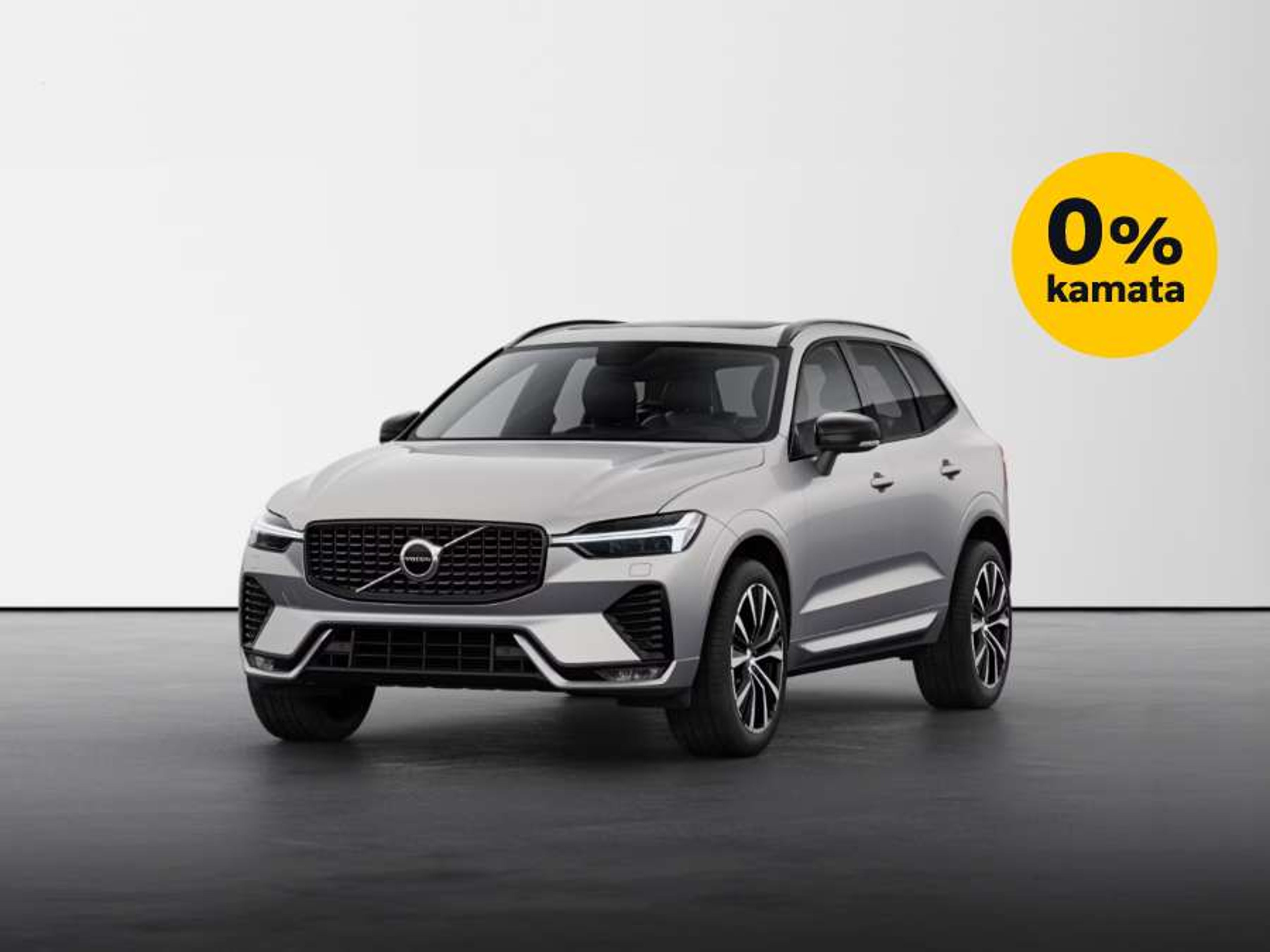Srebrni Volvo XC60 parkiran u studijskom okruženju s bijelom pozadinom, uz oznaku '0% kamata' u žutom krugu u gornjem desnom kutu.