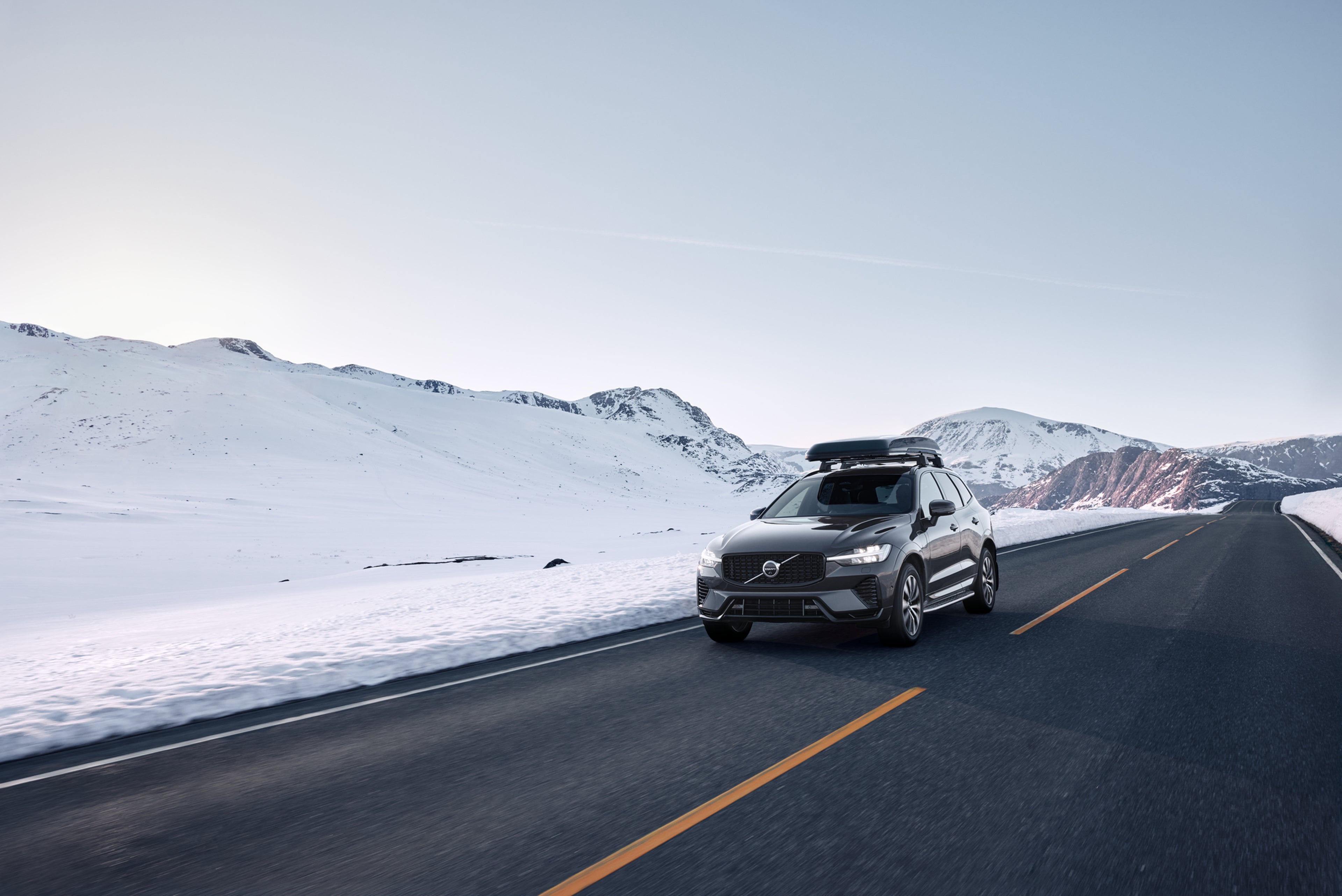 Vedere frontală a unui Volvo XC60 cu boxa pe acoperiș care se deplasează pe un drum