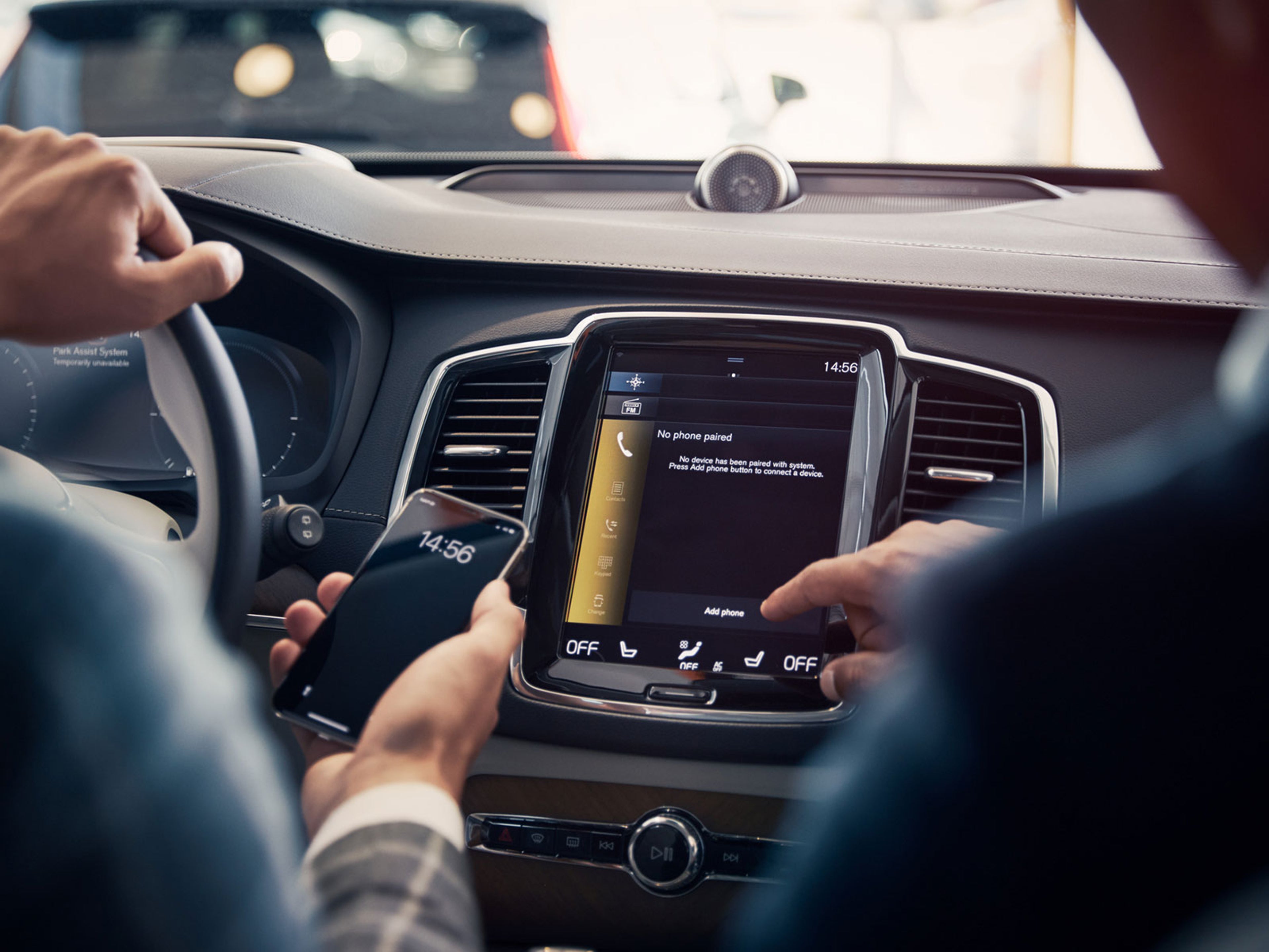 Менеджер показывает клиенту как подкчить телефон к автомобилю Вольво