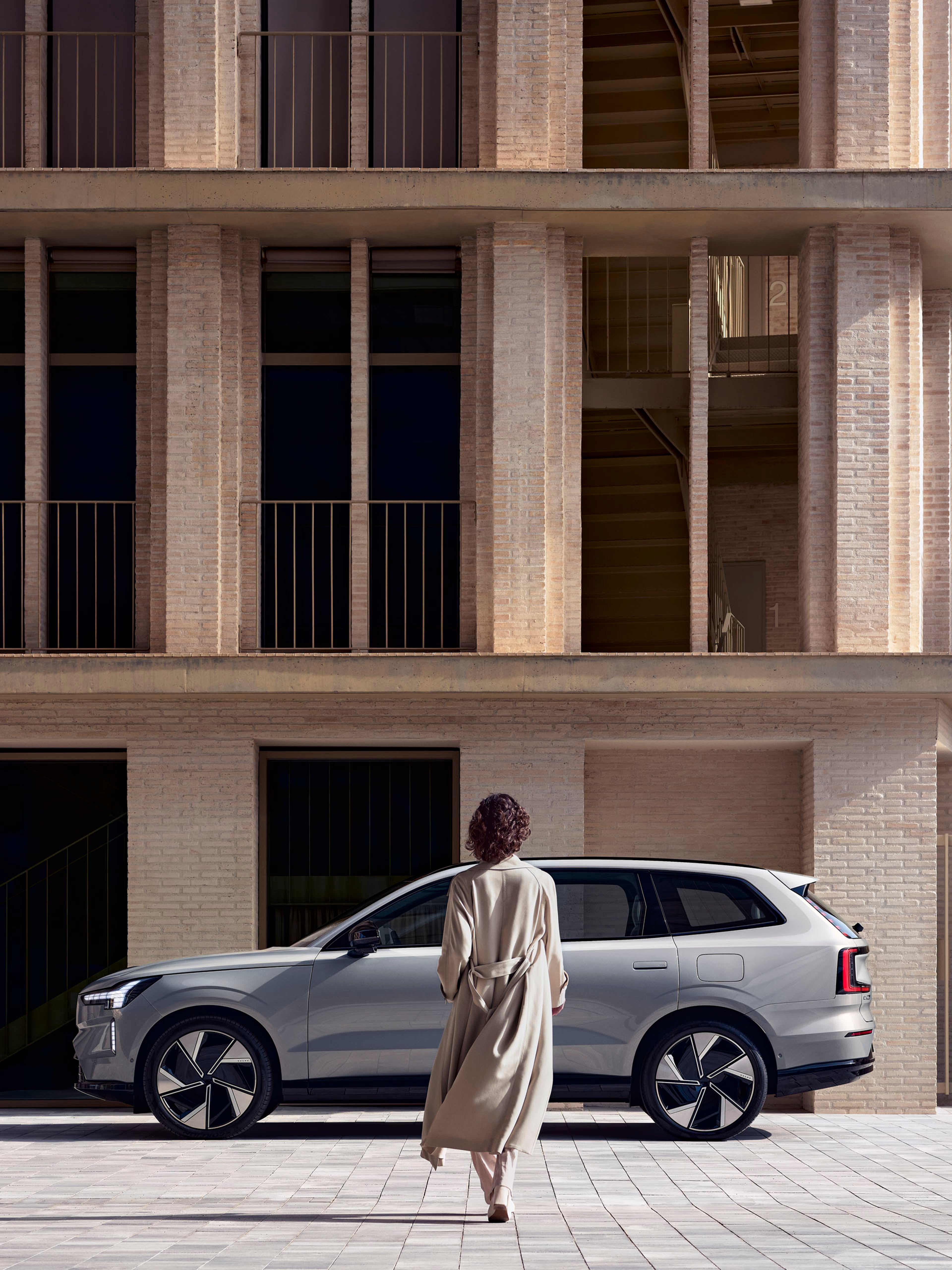 Una mujer caminando hacia un Volvo EX90 eléctrico