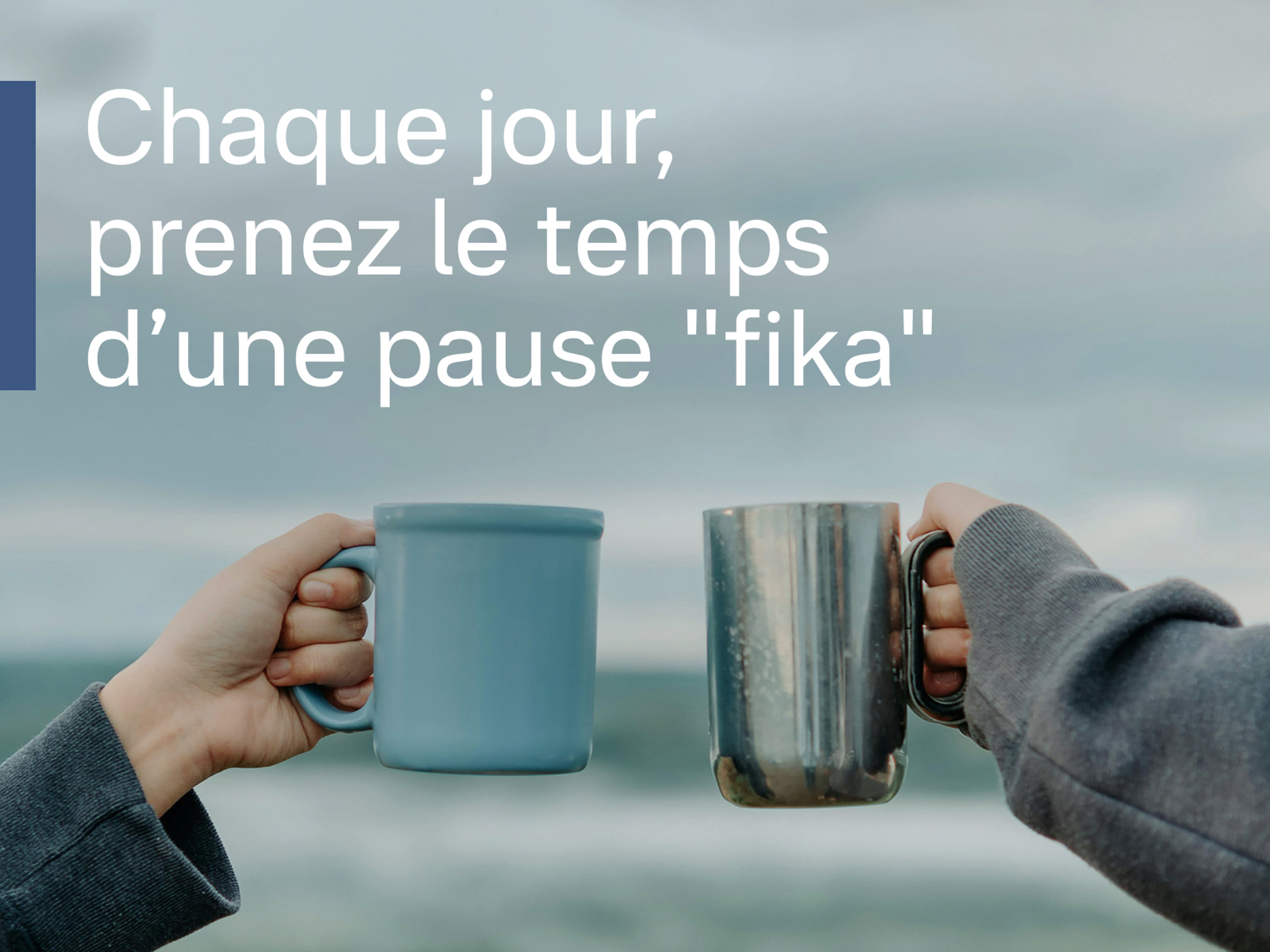 Deux mains trinquent avec des tasses devant un paysage serein, avec du texte blanc au premier plan : Chaque jour, prenez le temps d’une pause "fika".