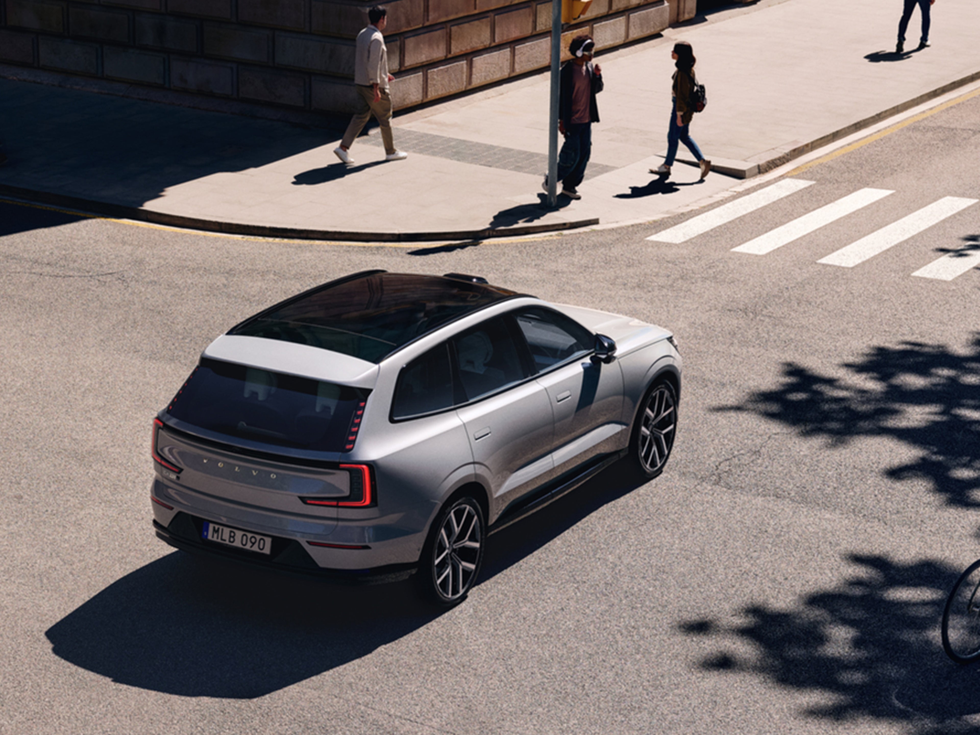 Vapour Grey -värinen Volvo EX90 täyssähköauto pysähtyneenä suojatien eteen päästämään kävelijät tien yli.