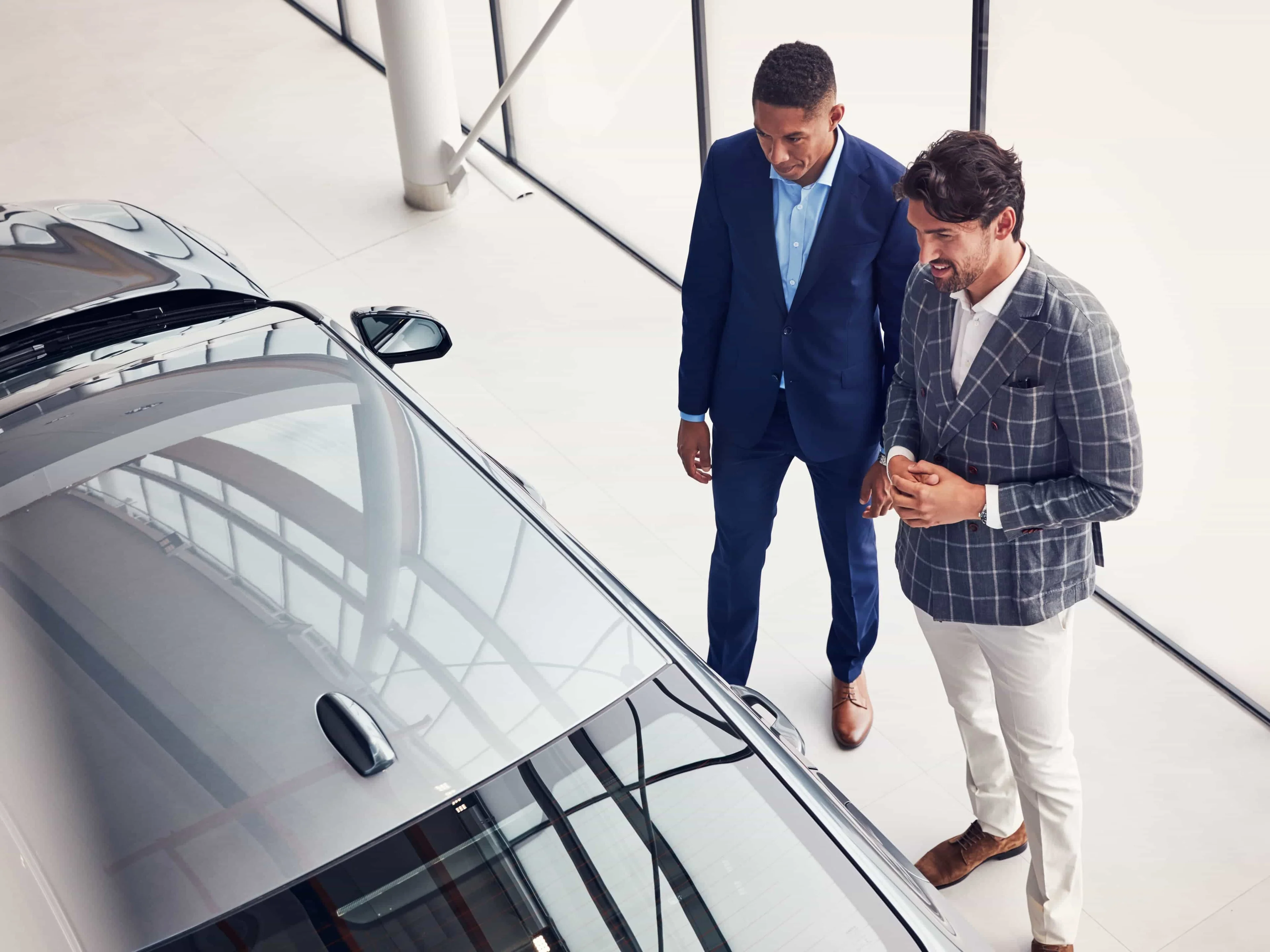 Deux hommes en costume regardent une Volvo dans le showroom.