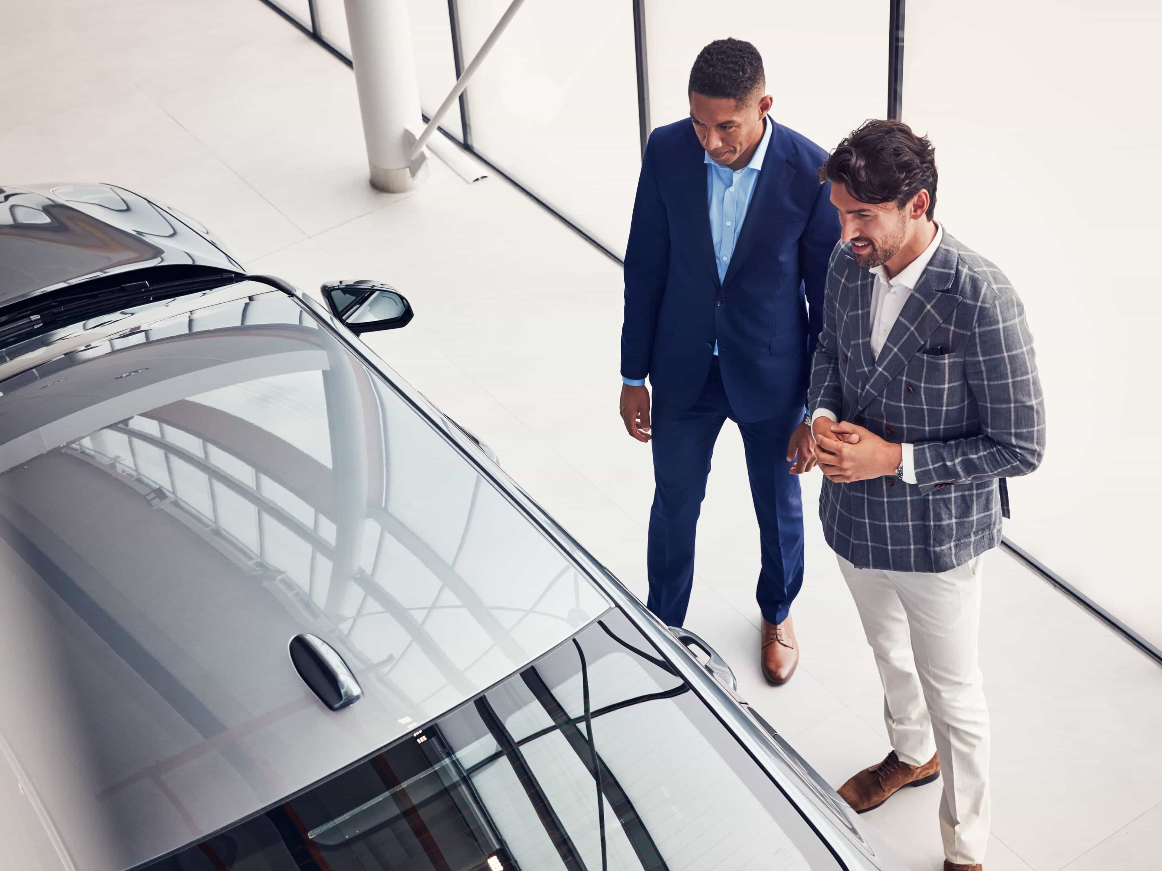 Twee mannen in maatpak bekijken een Volvo in de toonzaal.