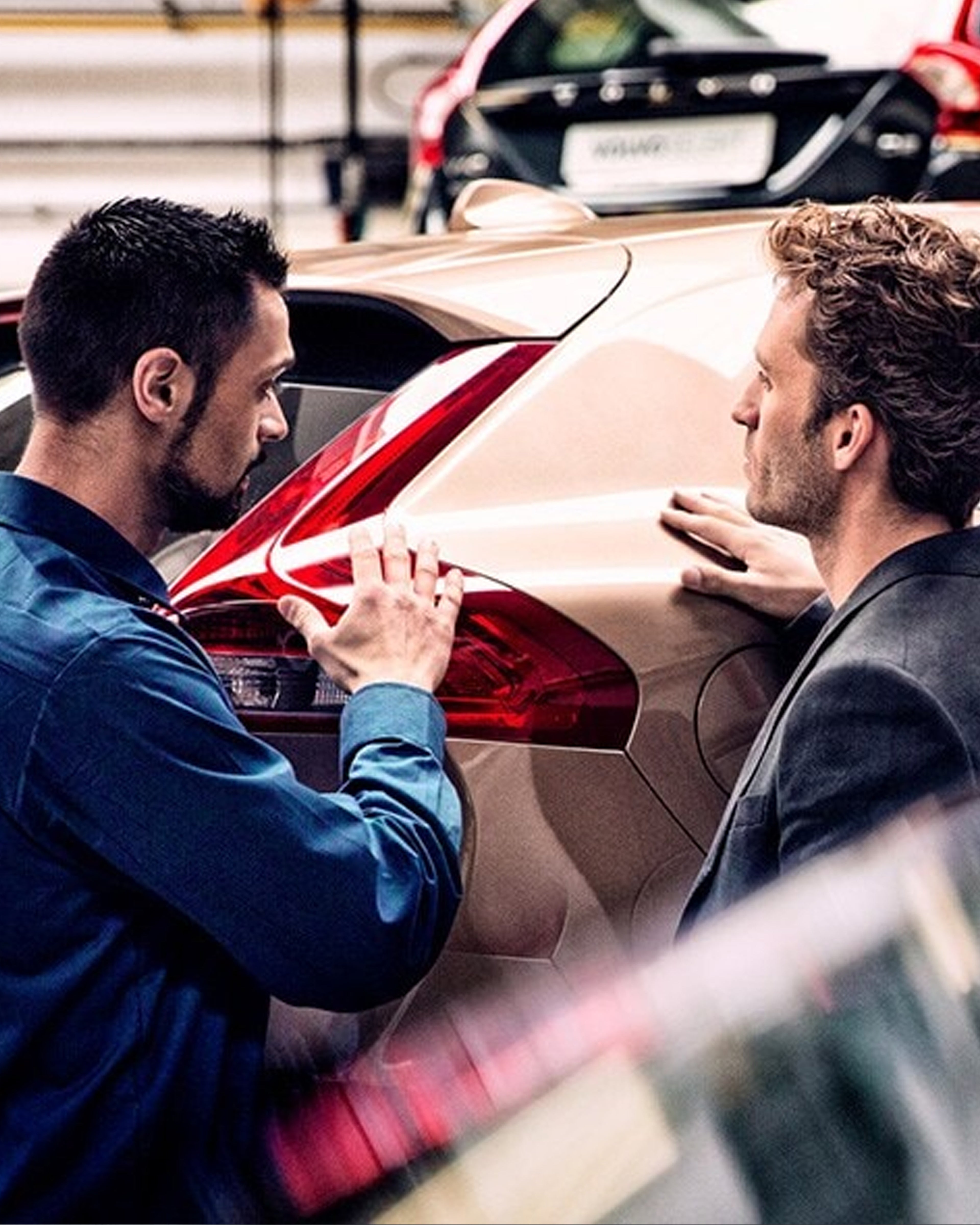 Volvoansatt snakker med kunde mens de ser på bilen på verksted