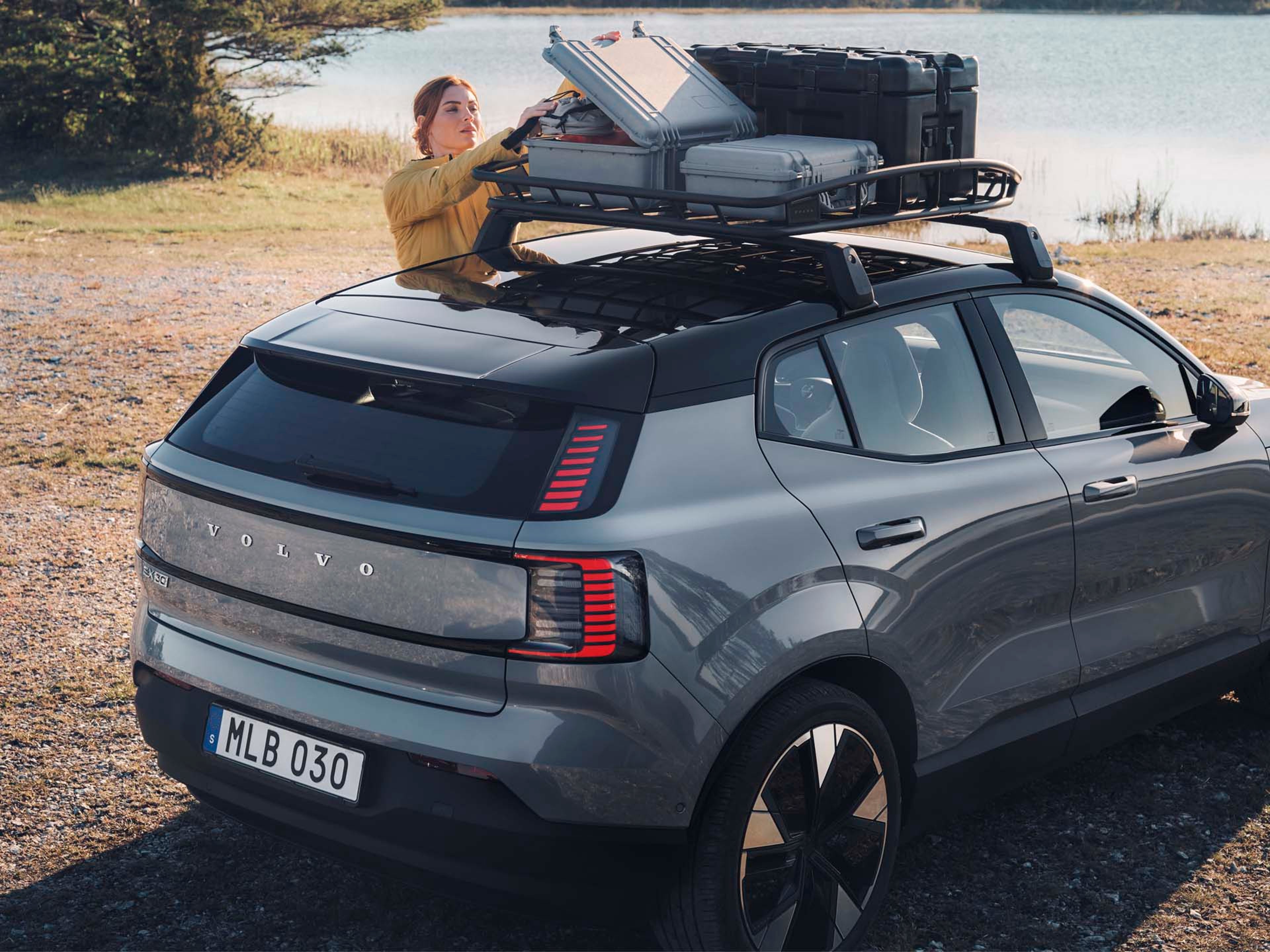 Una mujer cargando en una cesta de techo de un Volvo EX30 eléctrico