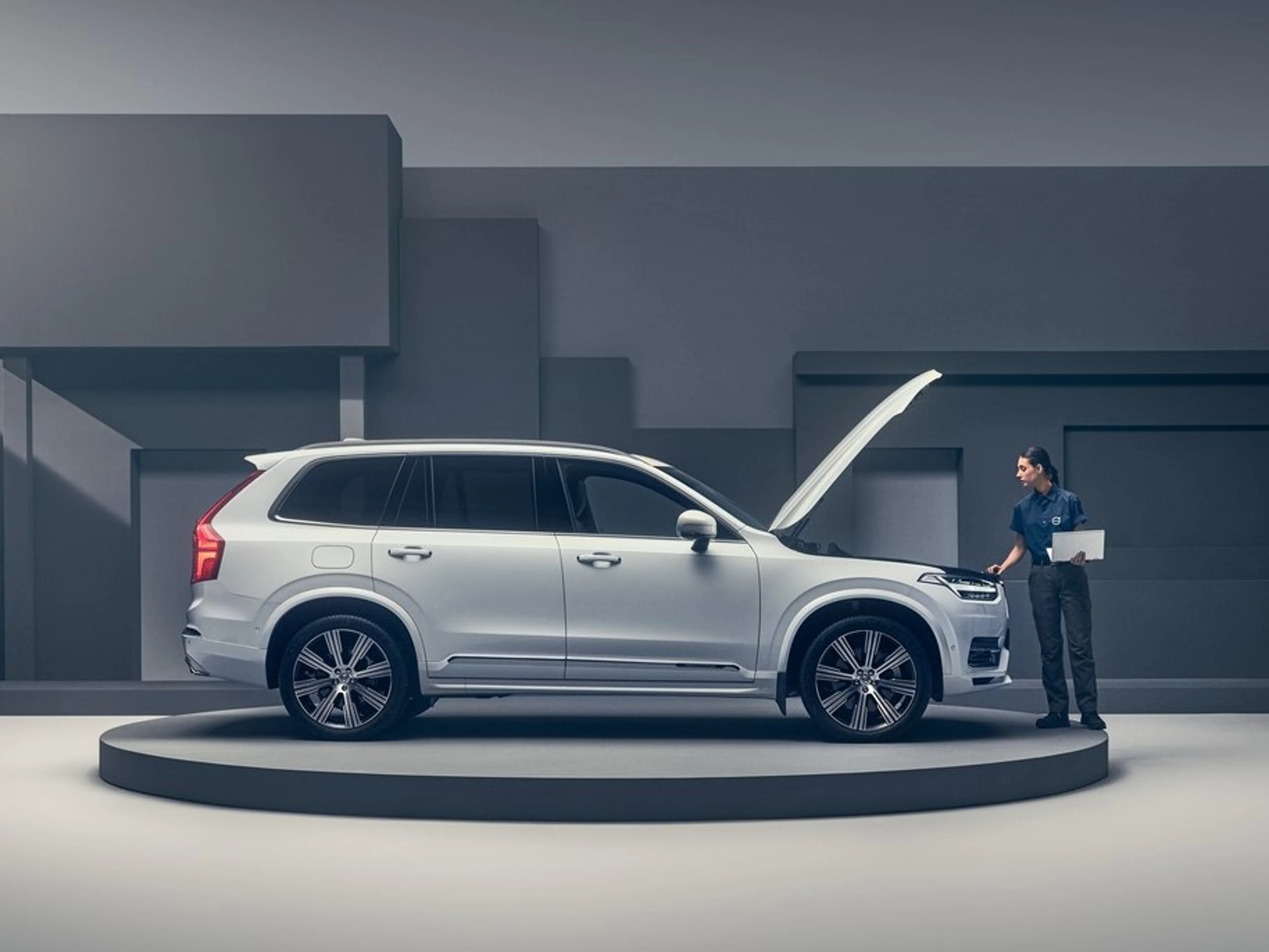 White Volvo with raised hood being worked on by female technician.