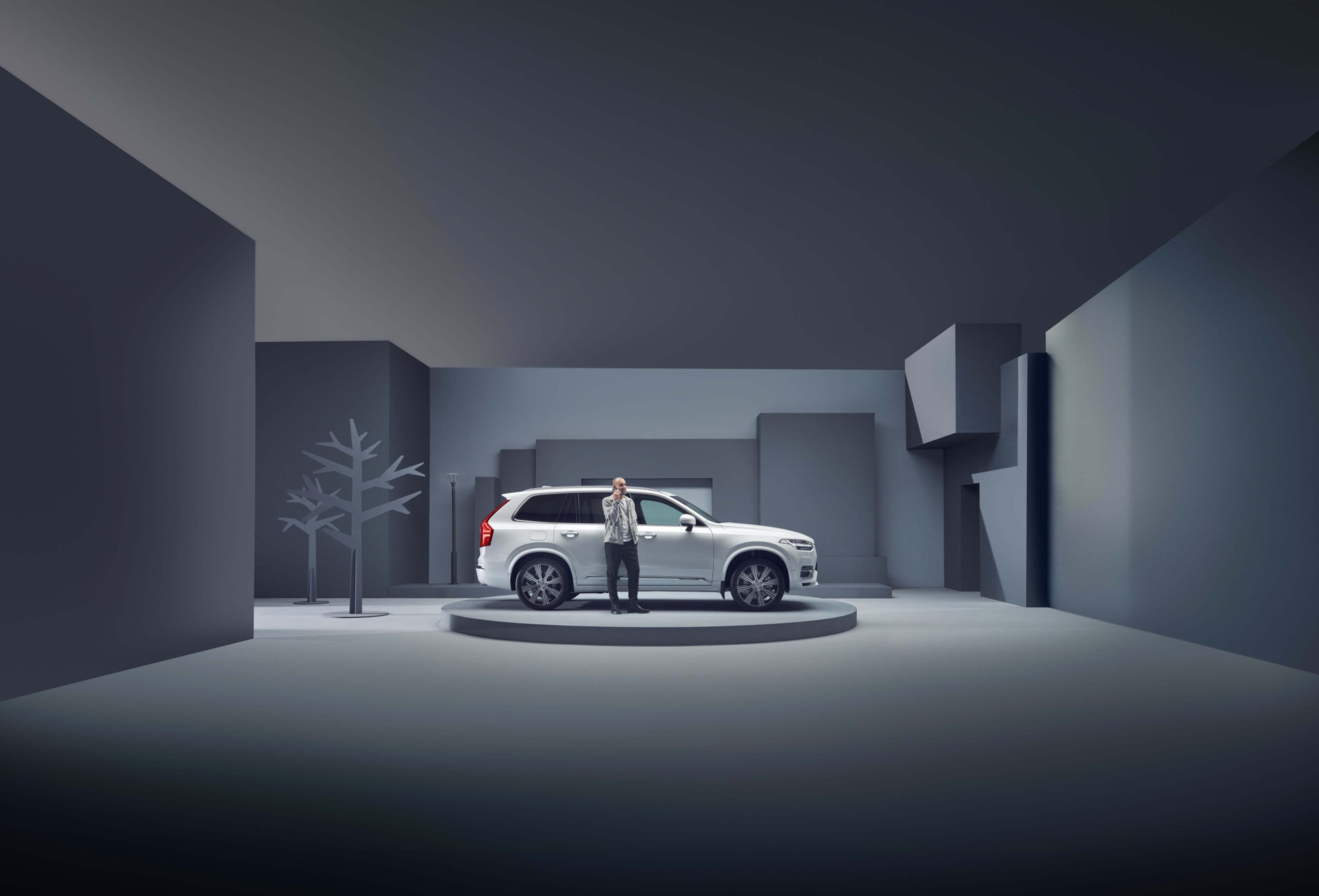Hvit XC90 med en mann utenfor, i studiomiljø og gråblå bakgrunn
