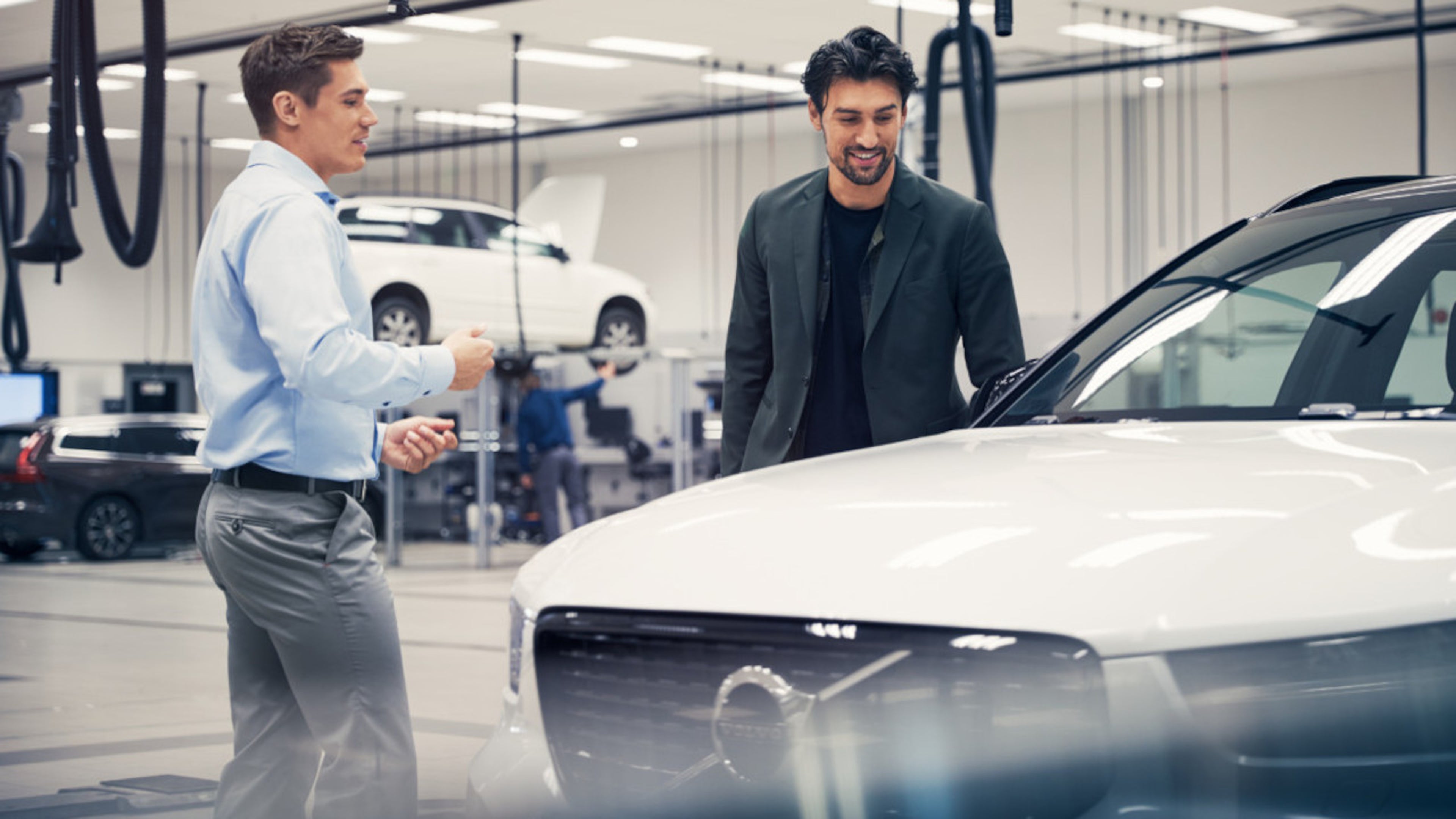 Zwei Männer stehen neben einem Volvo in einer Halle