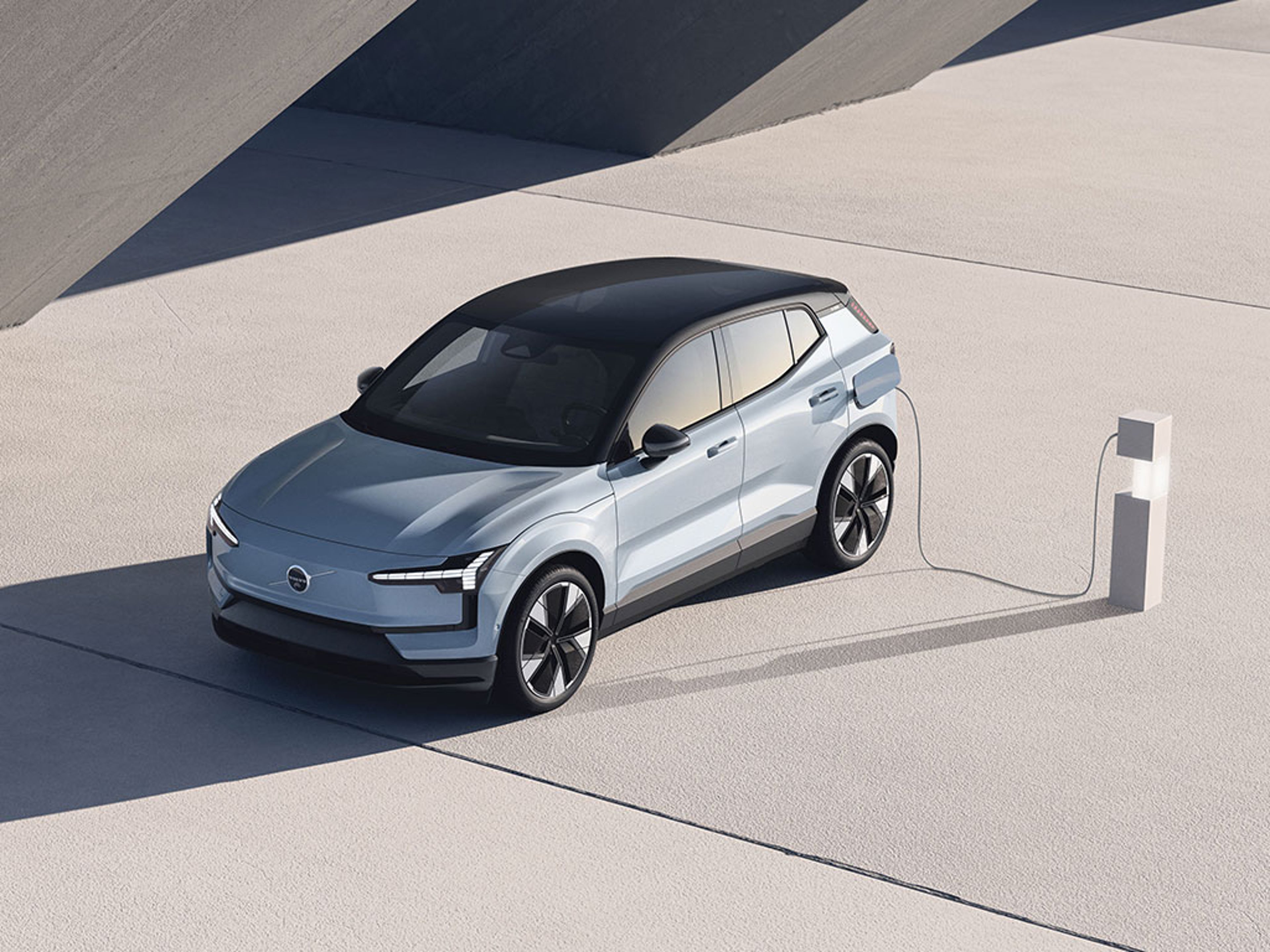 Petit SUV Volvo EX30 Bleu Nuage en charge vu de 3/4 avant dans un décor moderne