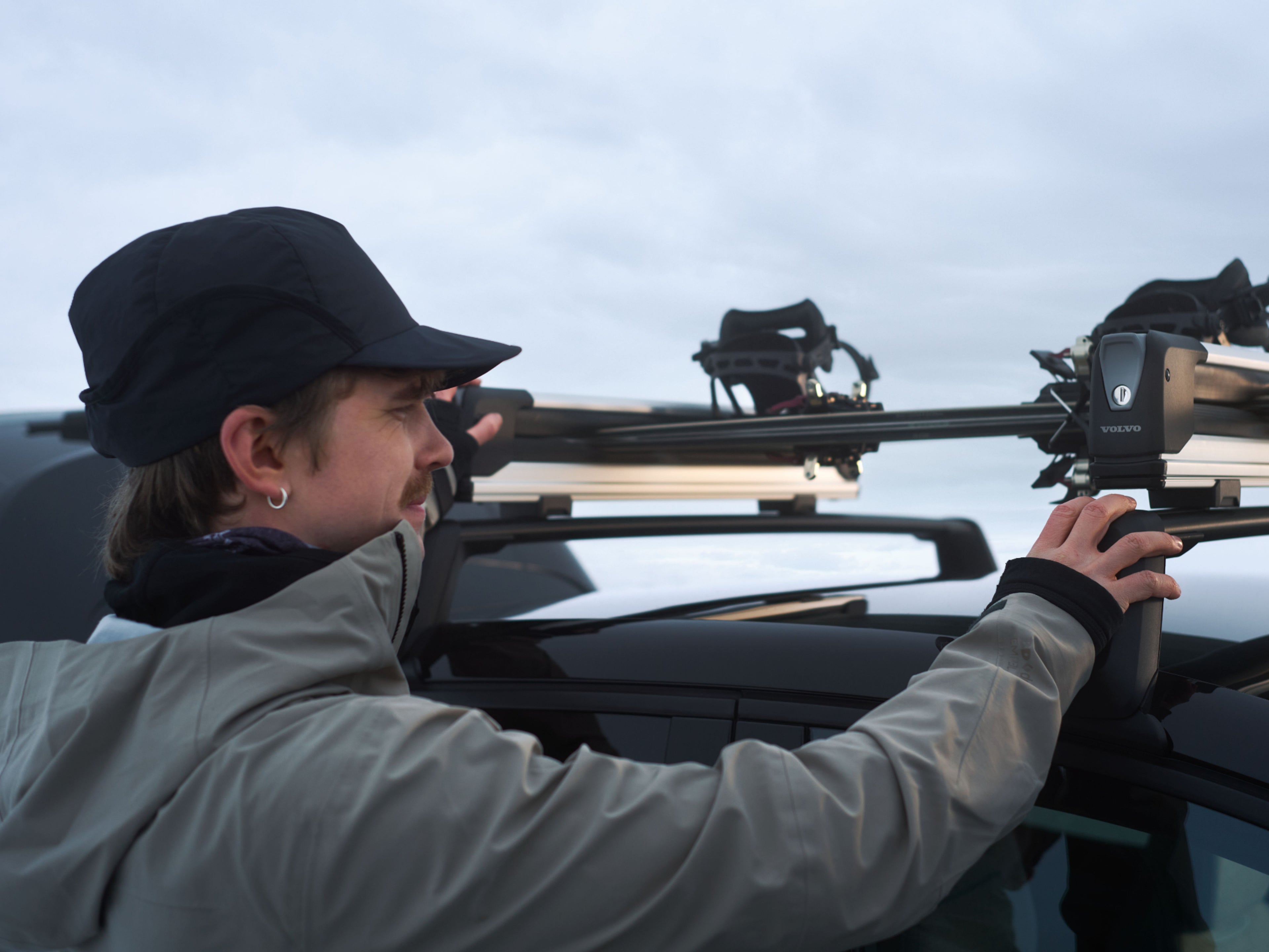 Ein Mann befestig Skier auf dem Dach eines Fahrzeugs.