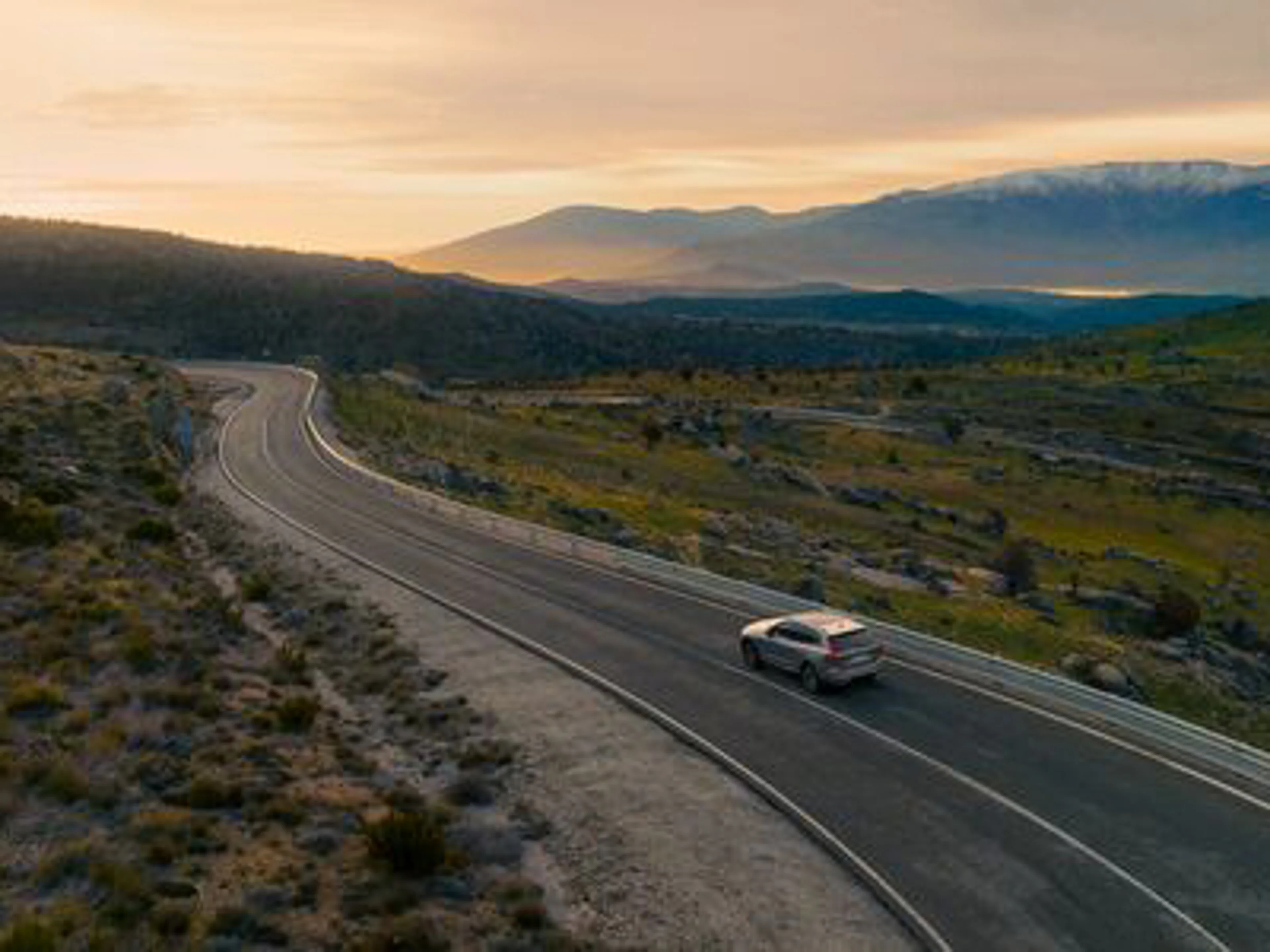 Volvo driving on road with sunset background