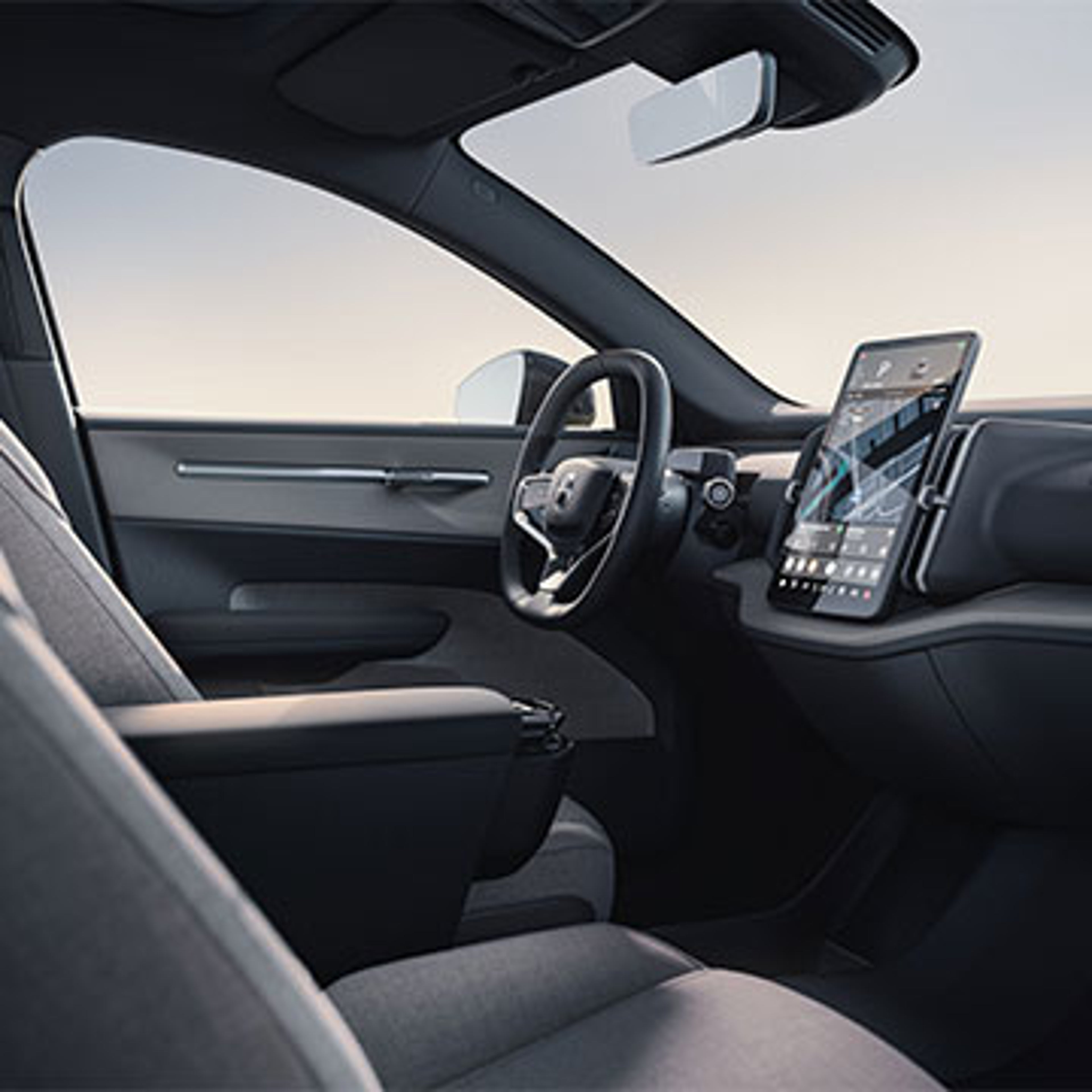 Intérieur d’une voiture Volvo EX30 moderne avec écran tactile affichant une carte, volant et sièges en tissu gris.