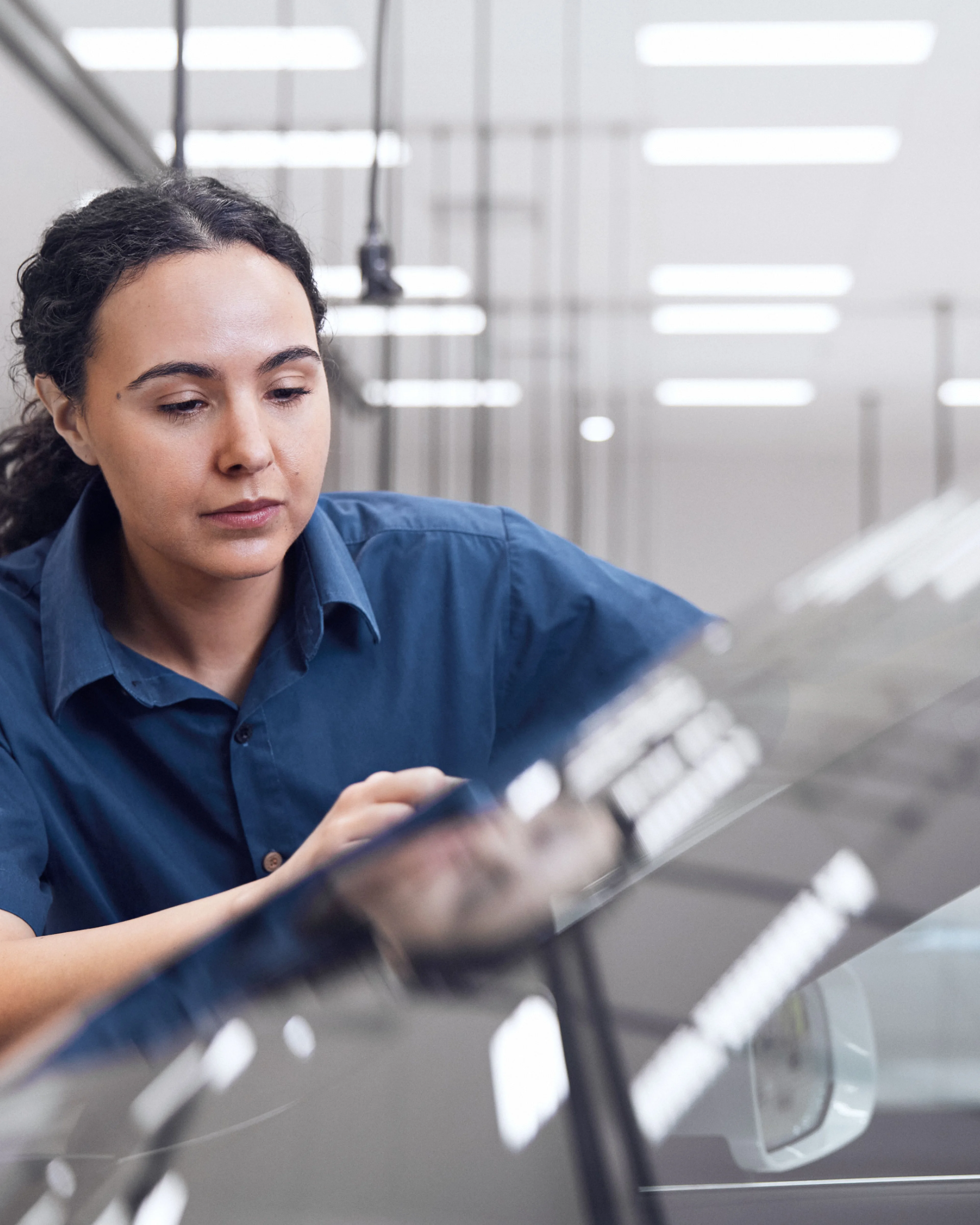 Eine weibliche Volvo Service Technikerin bearbeitet eine Glasscheibe.