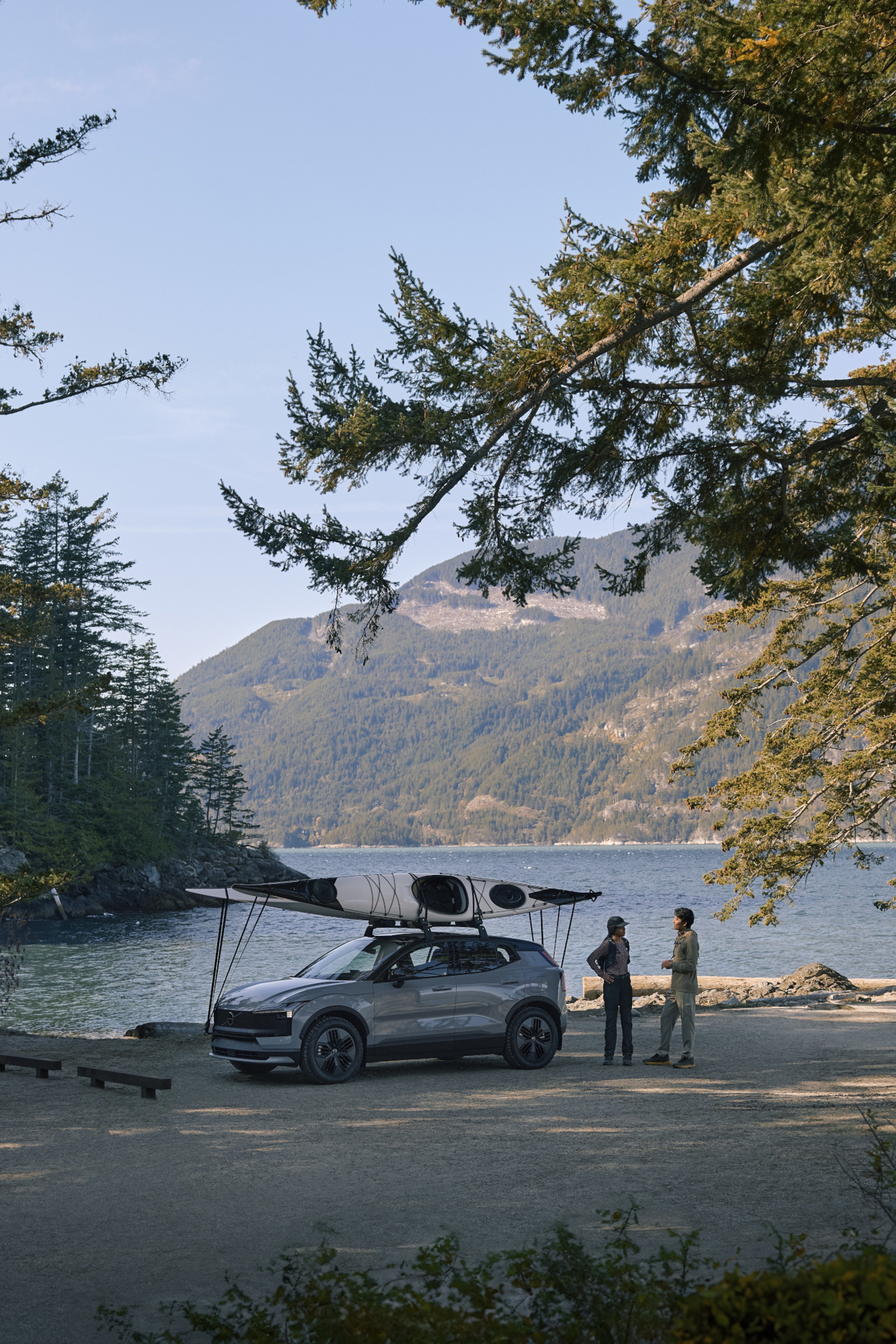 EX30 CC with kayak attached to the top next to two people talking beside a lake