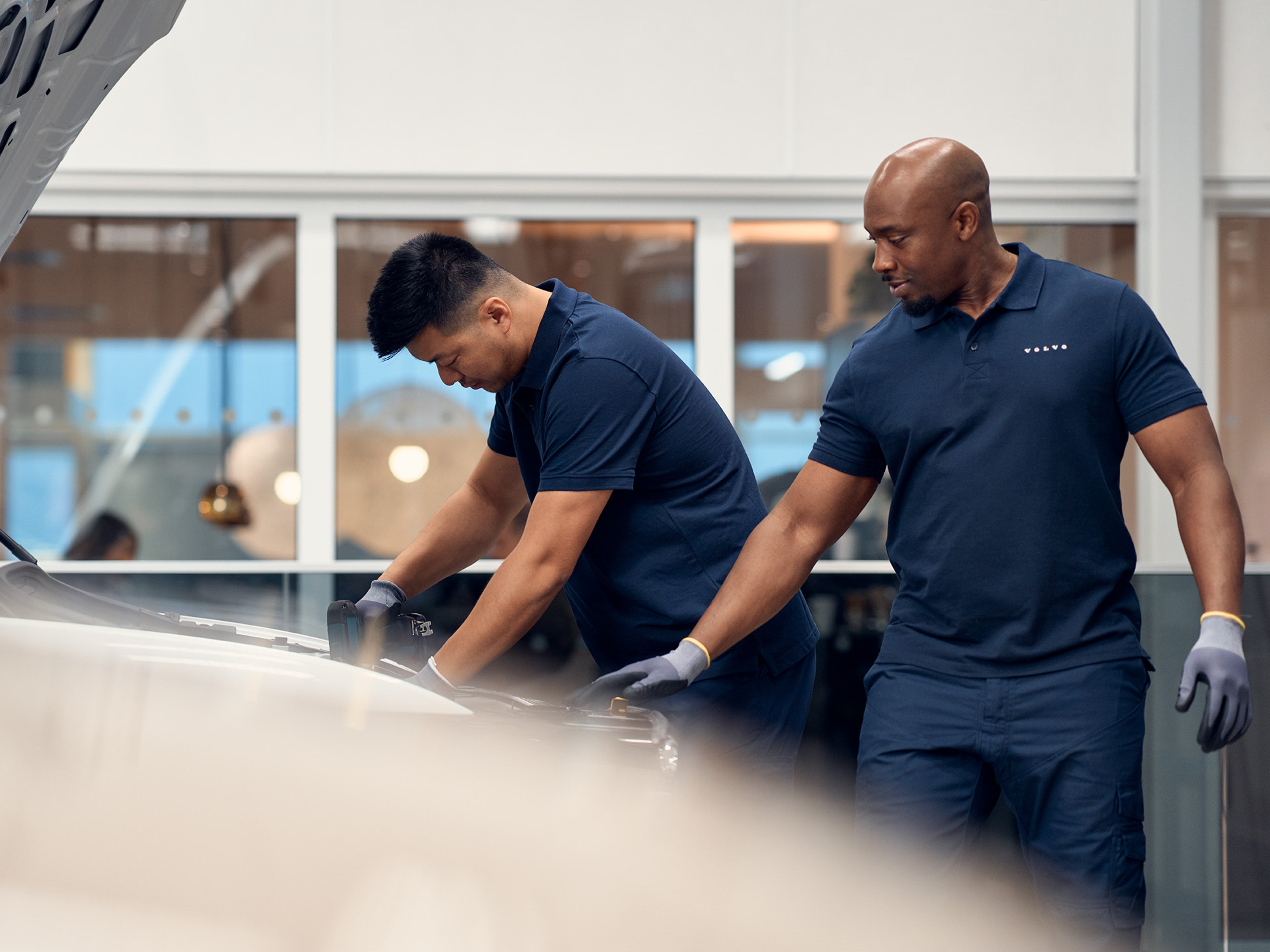 Dois homens vestidos de azul escuro a trabalhar numa oficina Volvo
