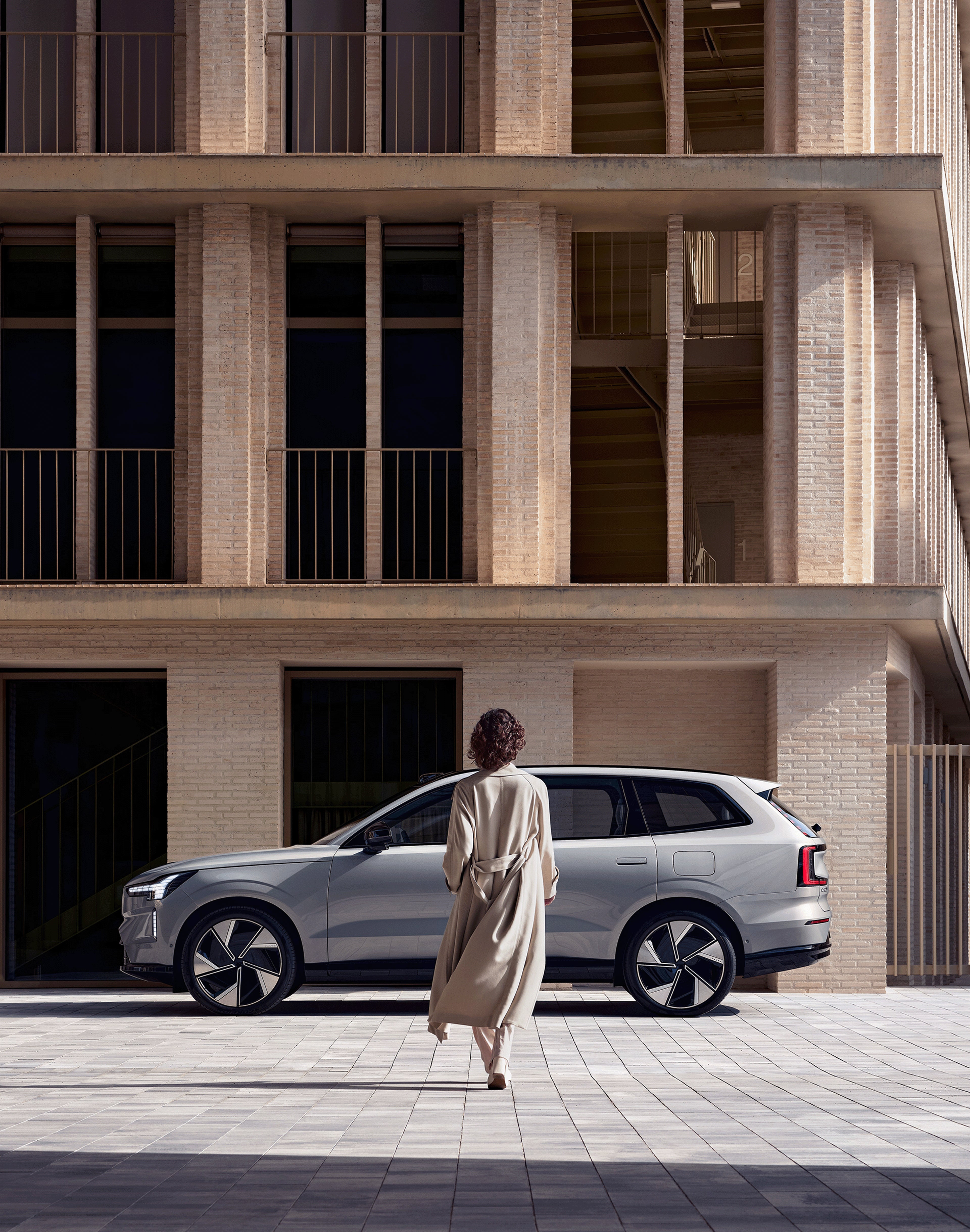 Eine Frau läuft auf einen Volvo EX90 zu.