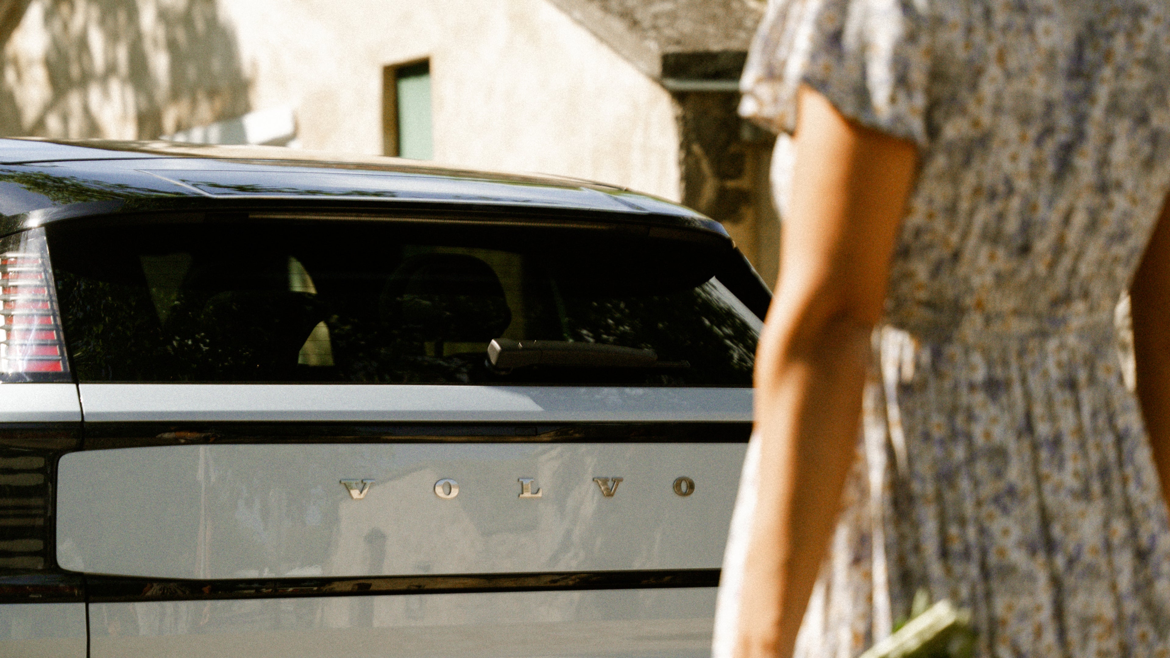 Eine weibliche Person steht vor einem weißen Volvo Fahrzeug.