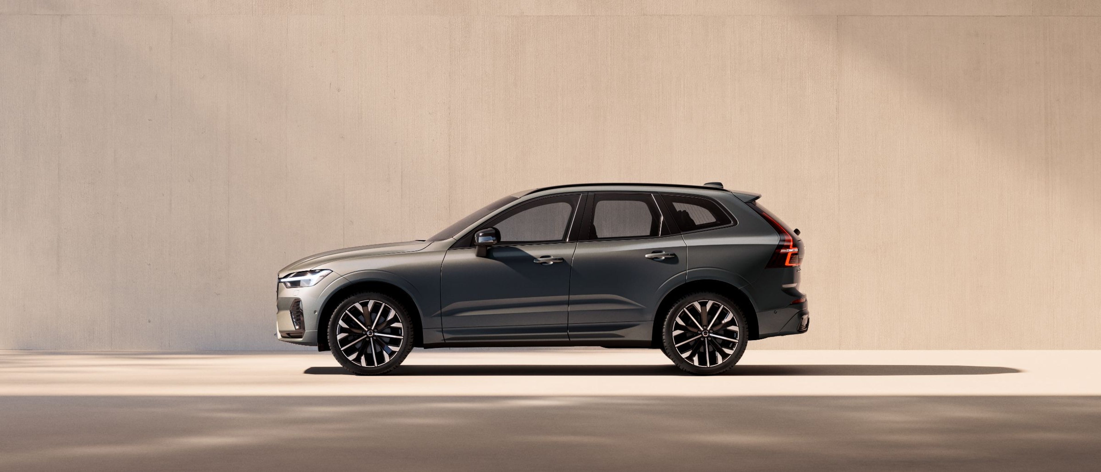 Сив Volvo XC60 SUV паркиран пред светол ѕид, страничен поглед.