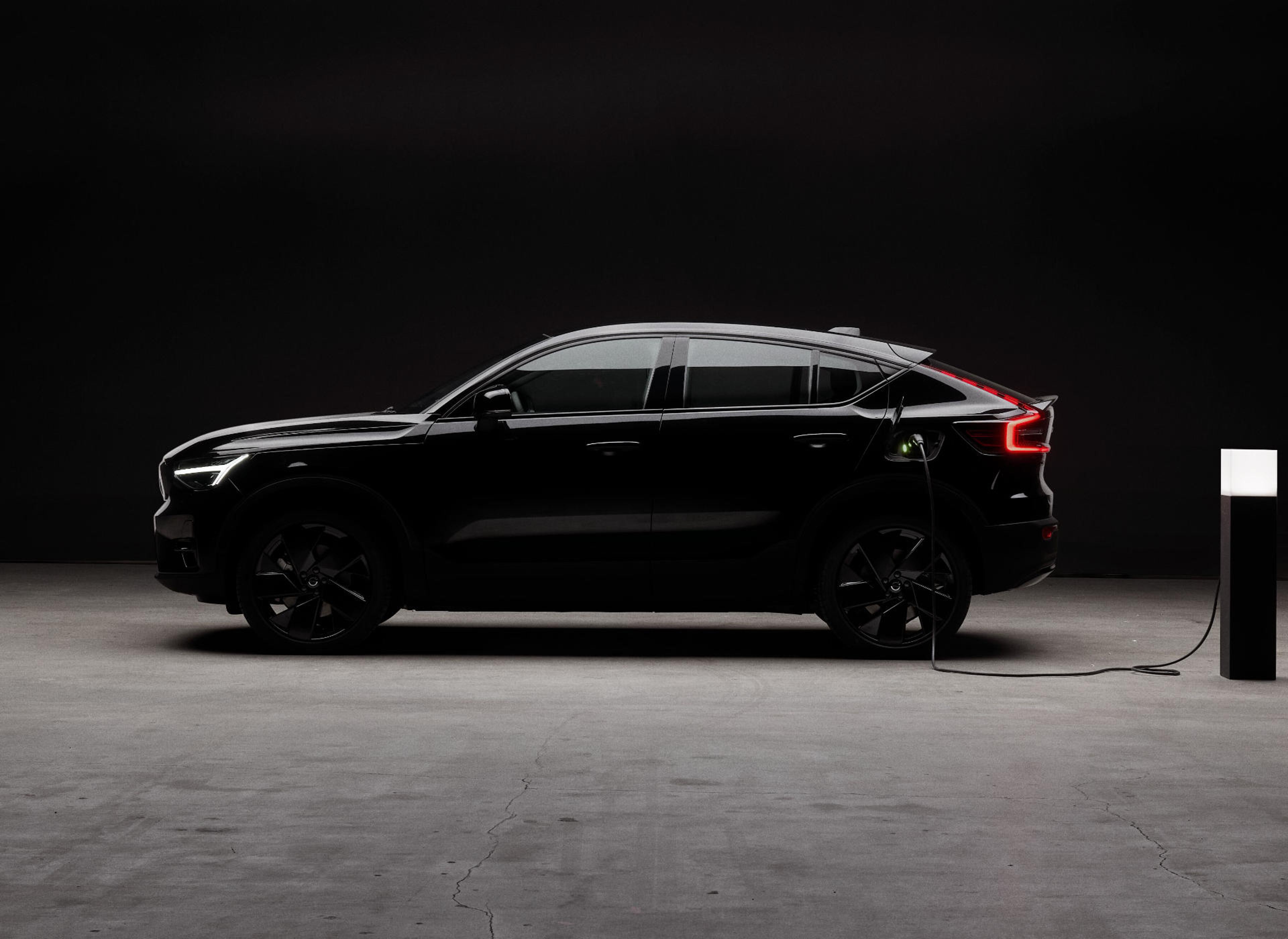 Seitenansicht eines tiefschwarzen Volvo EC90 Crossover vor einer schwarzen Wand.