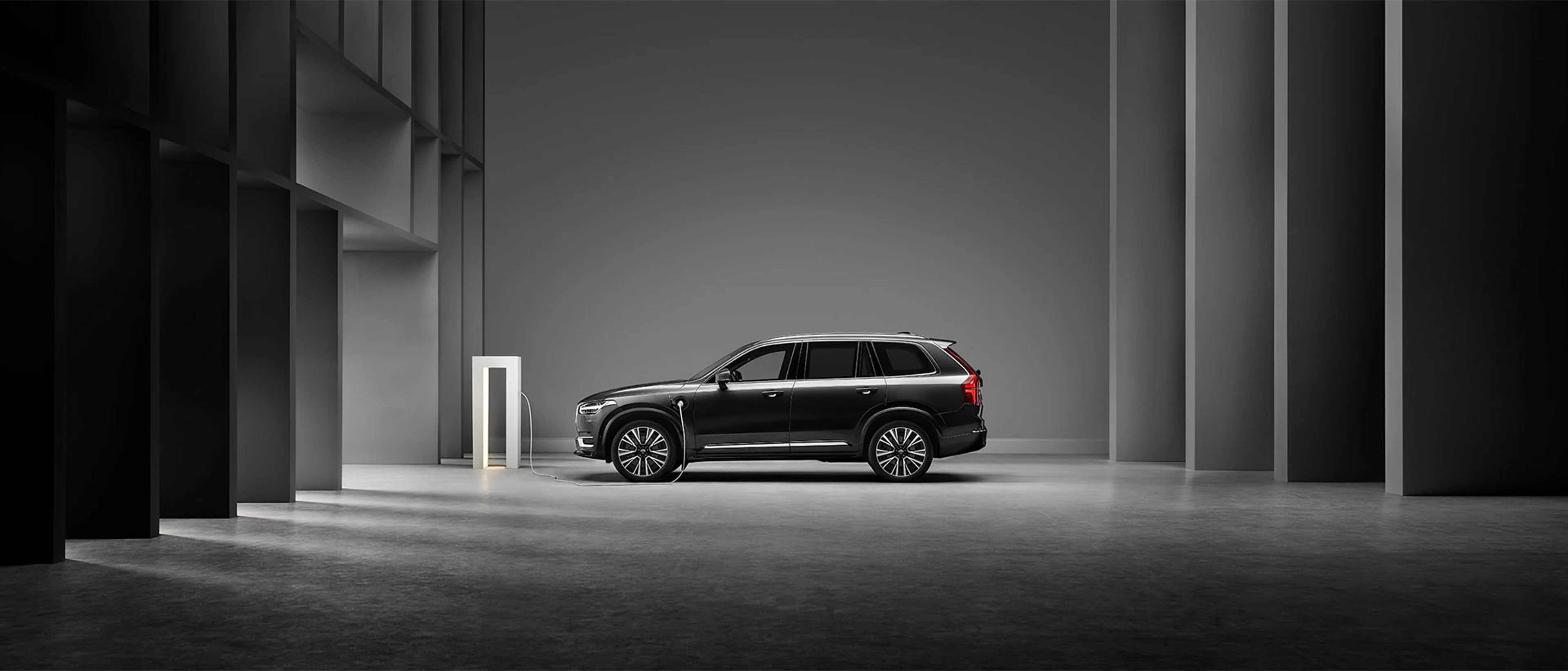 Voiture blindée noire en charge garée dans un espace moderne avec une lumière douce.