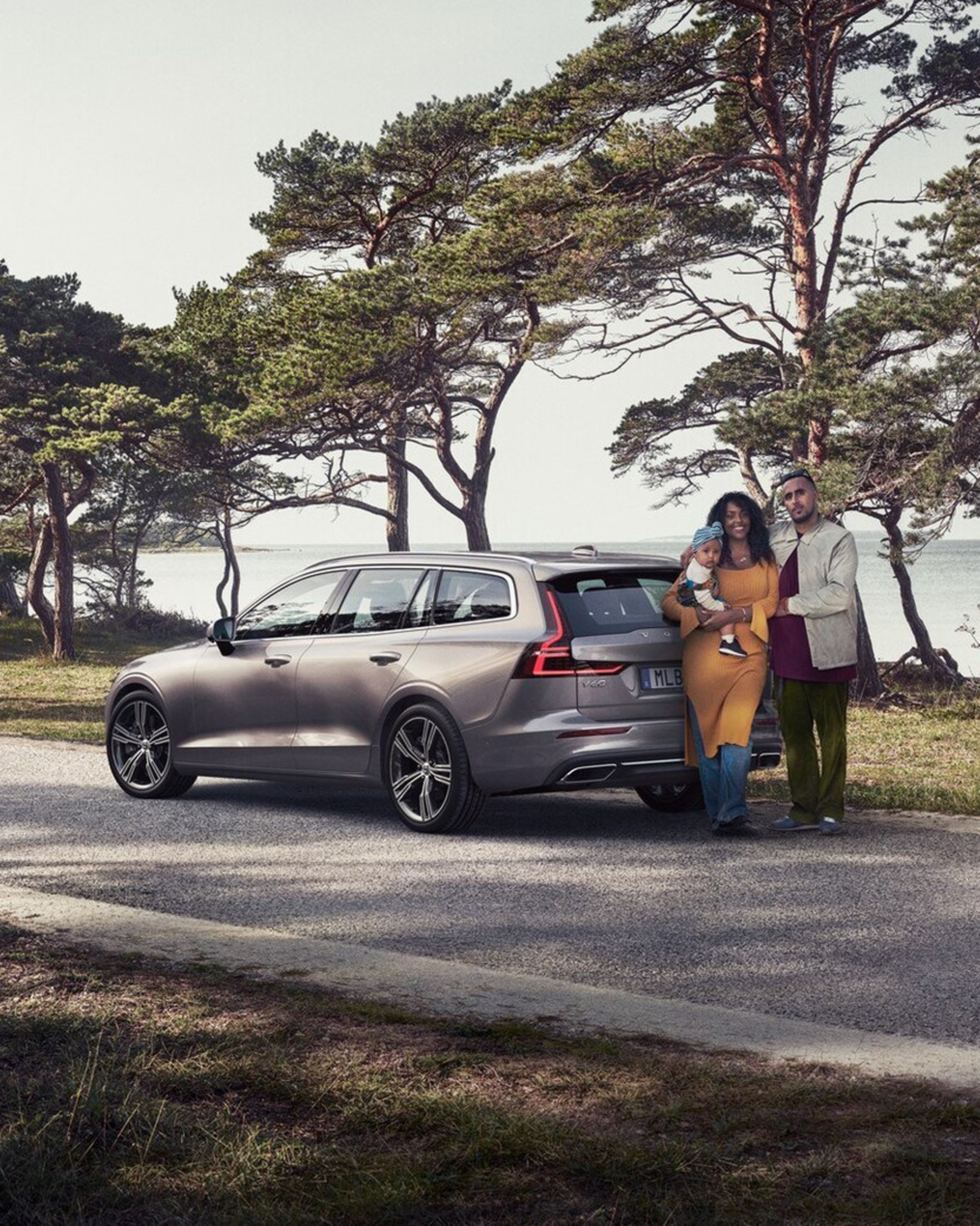 Familie stående bak en sølv Volvo stasjonsvogn