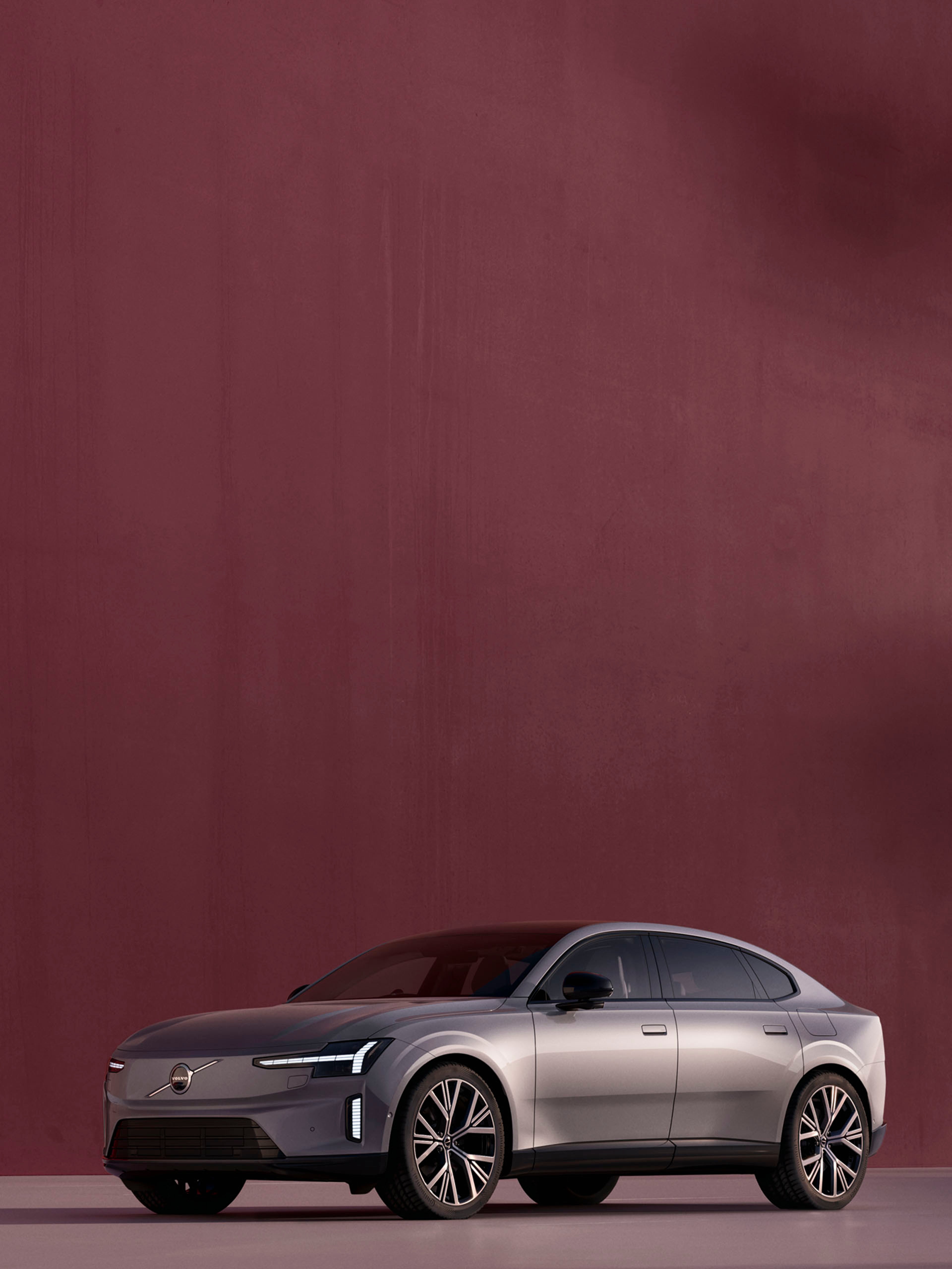 Un Volvo ES90 vista frontal lateral en color gris metalizado destacando sus llantas y su logo central.