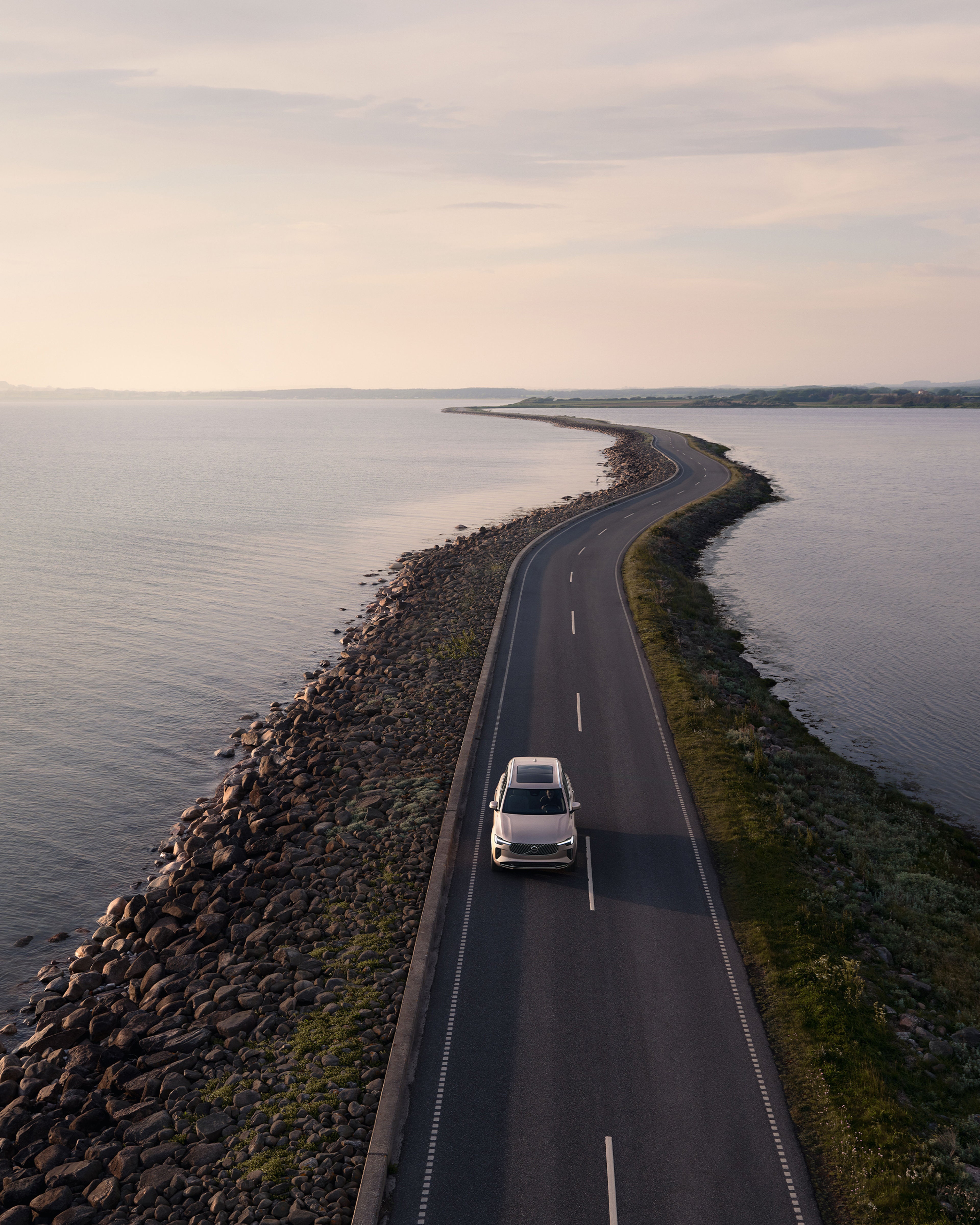Ein Volvo XC60 fährt eine Straße am Wasser entlang.
