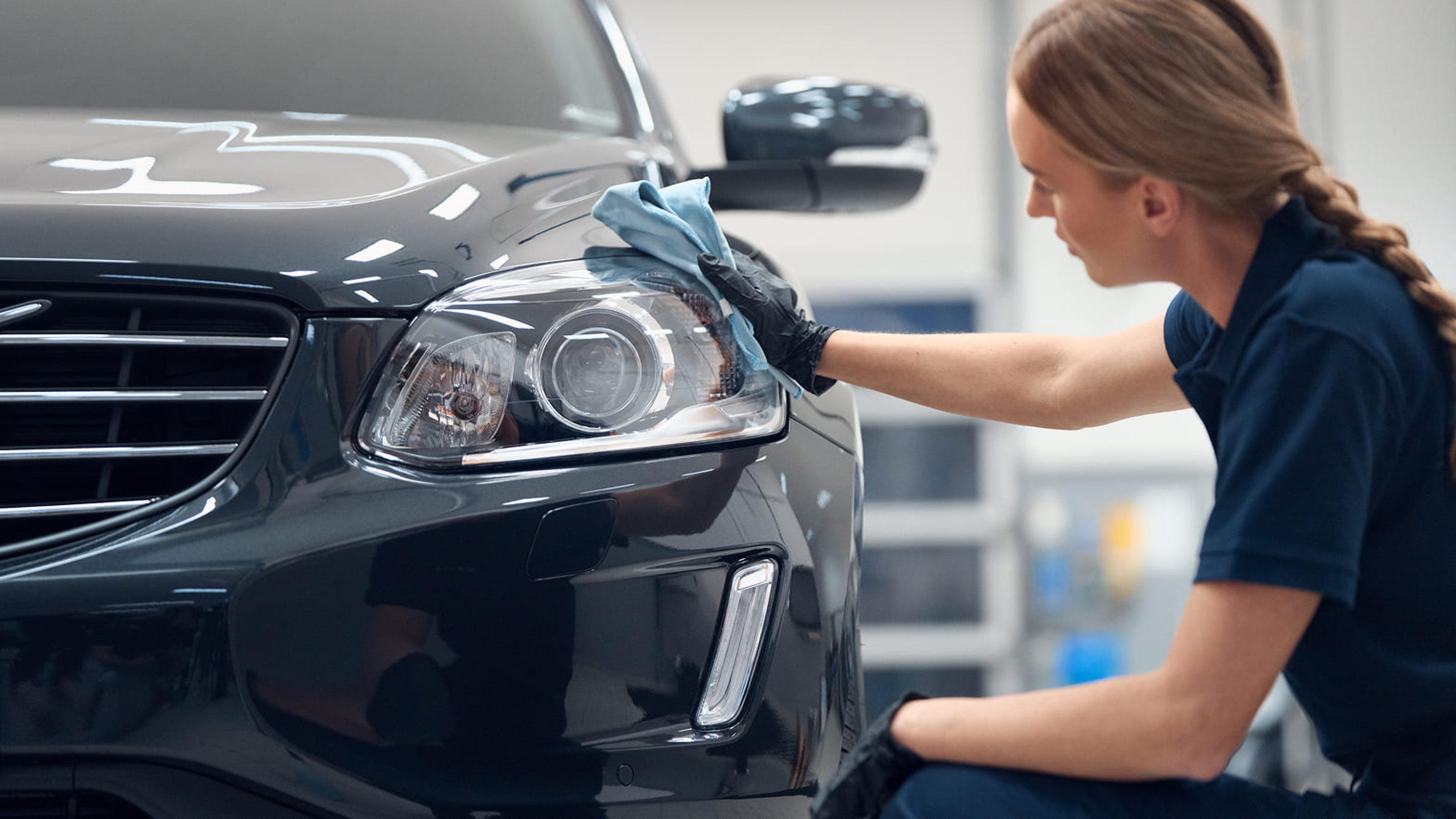 Volvo service tekniker som putsar en svart grå Volvo