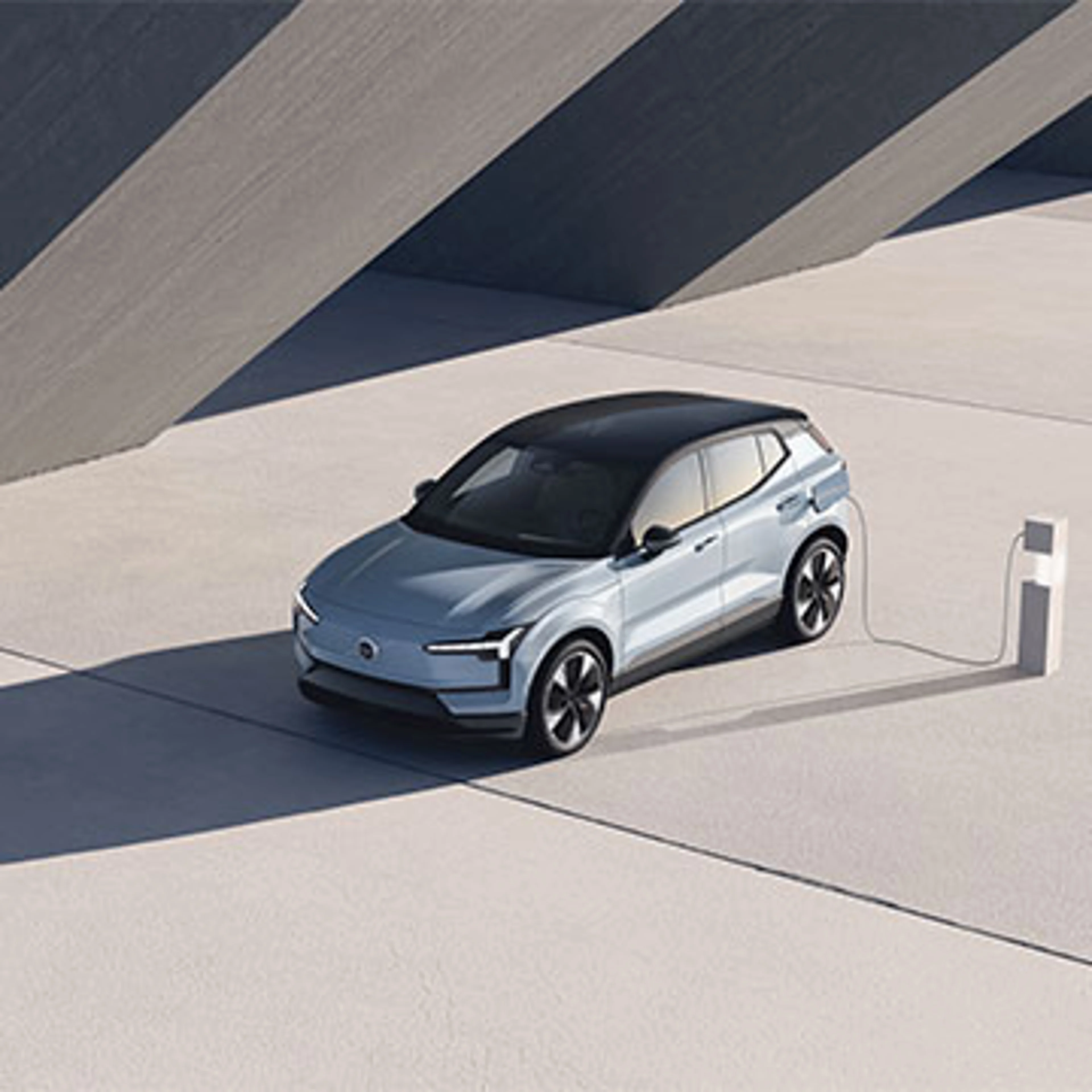 Volvo EX30 en charge dans une station au design minimaliste et ensoleillé
