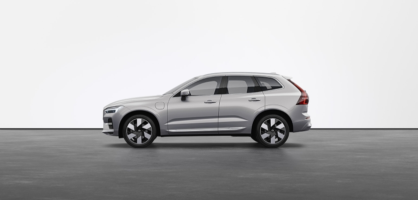 A silver Volvo XC60 Recharge plug-in hybrid SUV standing still on grey floor in a studio.