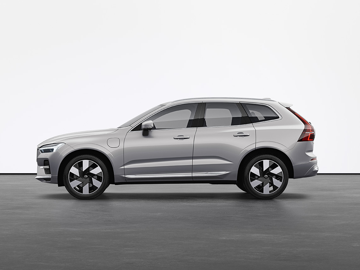 A silver Volvo XC60 Recharge plug-in hybrid SUV standing still on grey floor in a studio.
