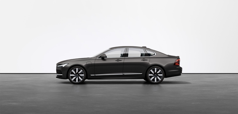 A black Volvo S90 Recharge standing still on grey floor in a studio.