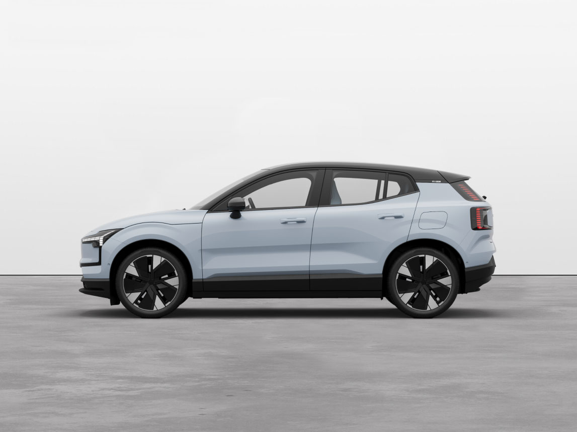 Side view of the fully electric Volvo EX30 in cloud blue standing still on grey floor in a studio.