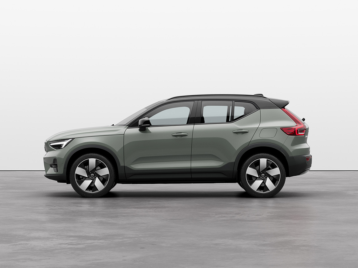 A green Volvo XC40 Recharge full electric compact SUV standing still on grey floor in a studio