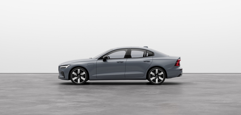 A red Volvo sedan S60 Recharge plugin hybrid standing still on grey floor in a studio