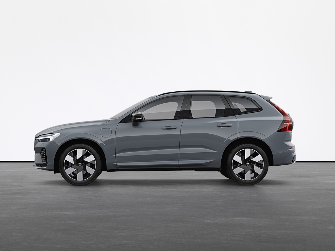 A vapour grey Volvo XC60 Recharge plug-in hybrid SUV standing still on grey floor in a studio.
