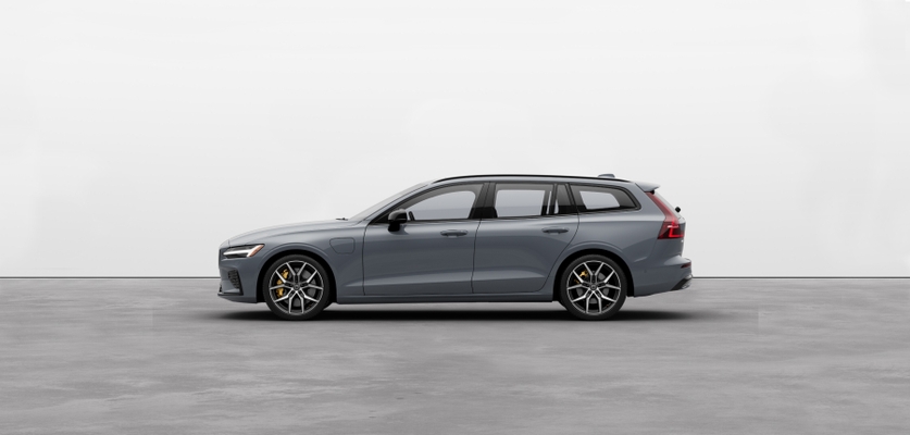 A luminous sand metallic Volvo V60 Recharge plugin hybrid standing still on grey floor in a studio