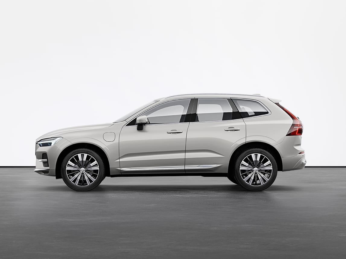 A silver Volvo XC60 Recharge SUV standing still on grey floor in a studio.