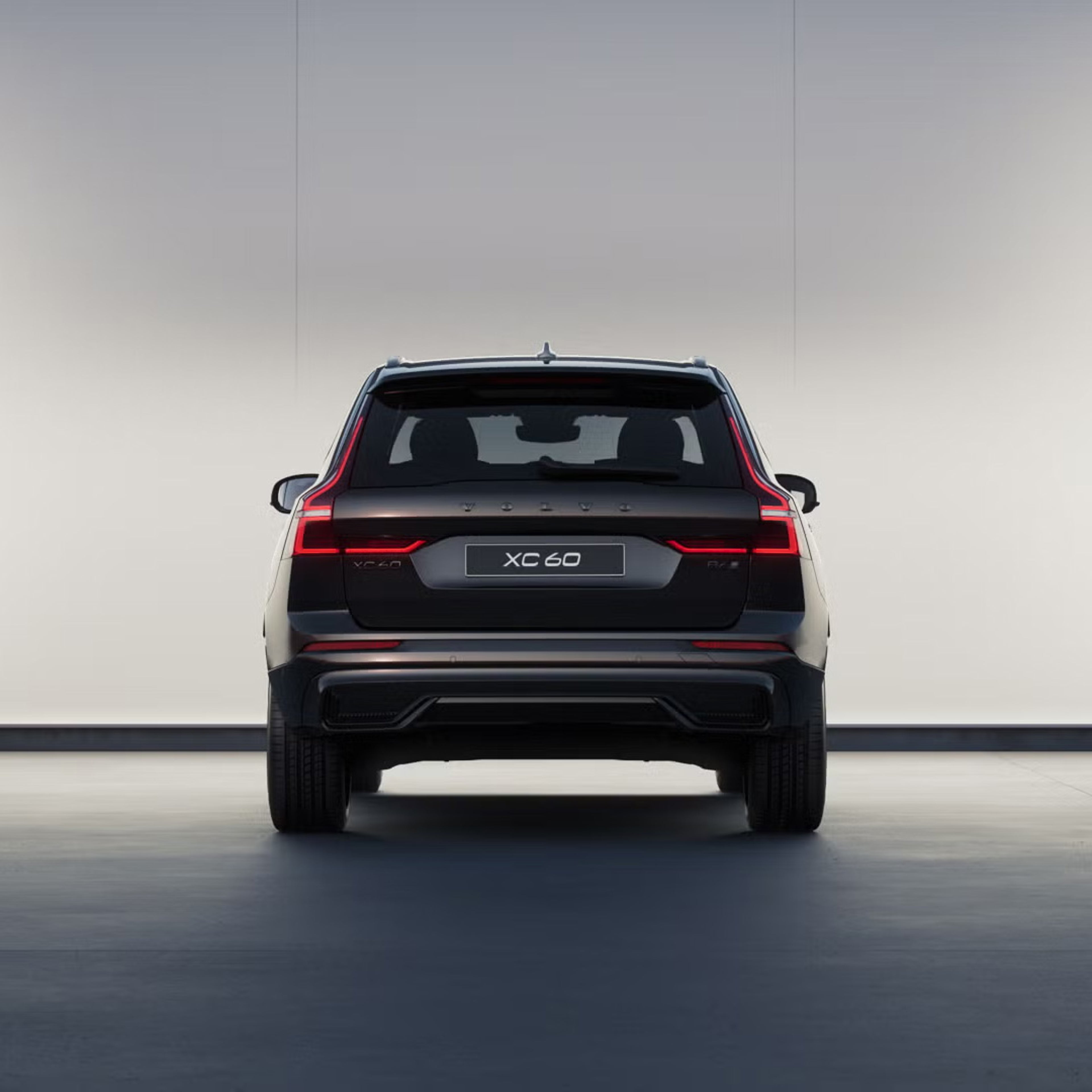 Rear view of XC60 black edition in front of a softly lit wall