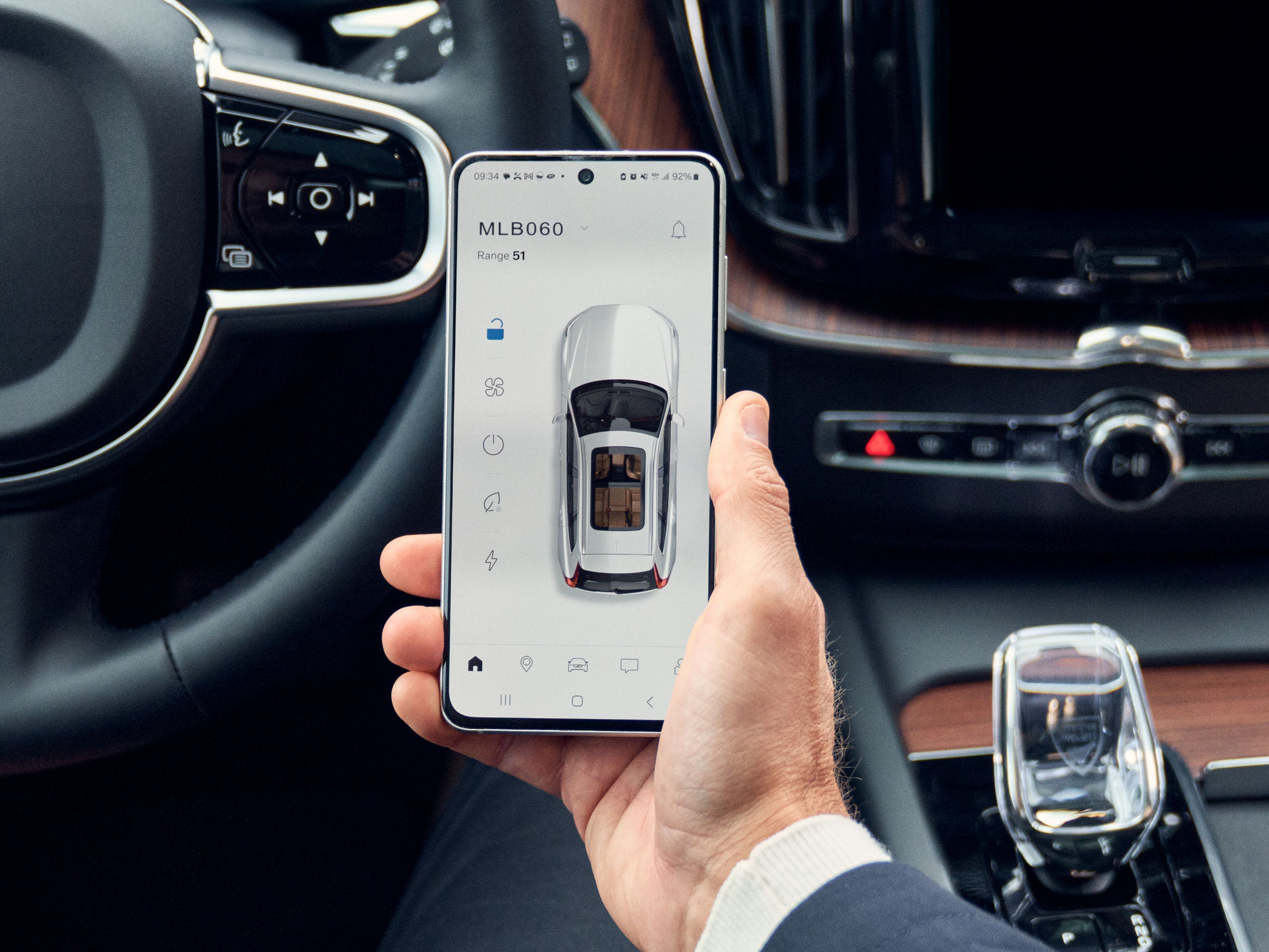 Muž prohlížející si telefon s Volvo Cars aplikací uvnitř vozu Volvo