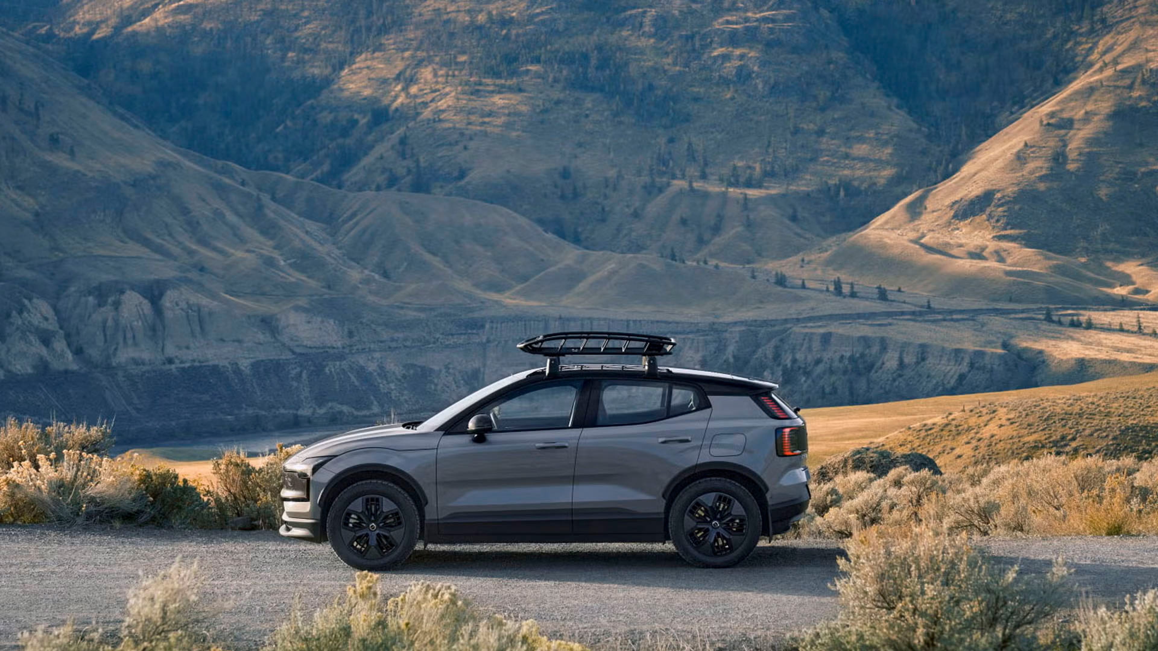 Side view of EX30 Cross Country against mountainous backdrop bathed in sunlight