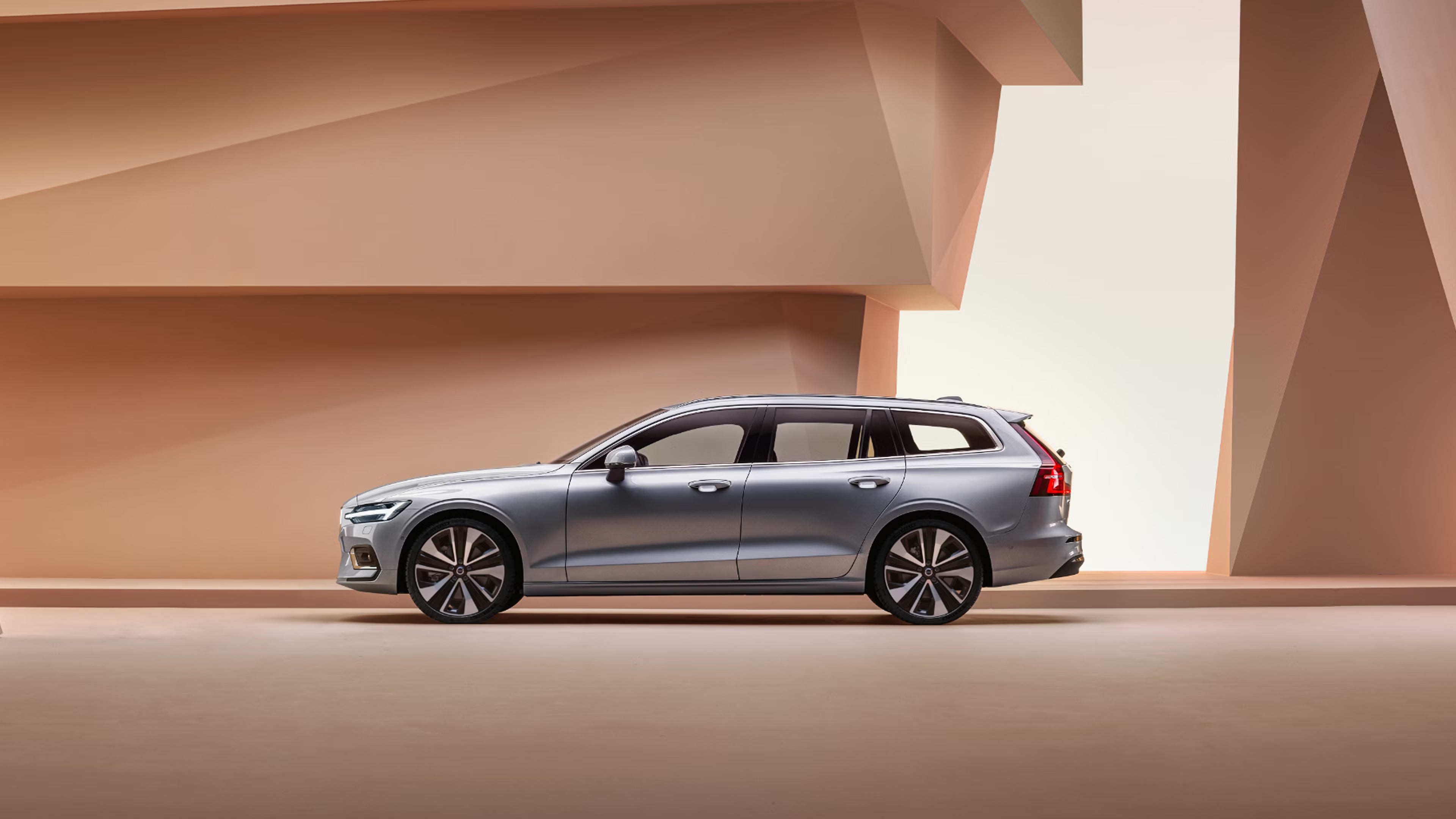 Side view of Volvo V60 on a light coral angular abstract background