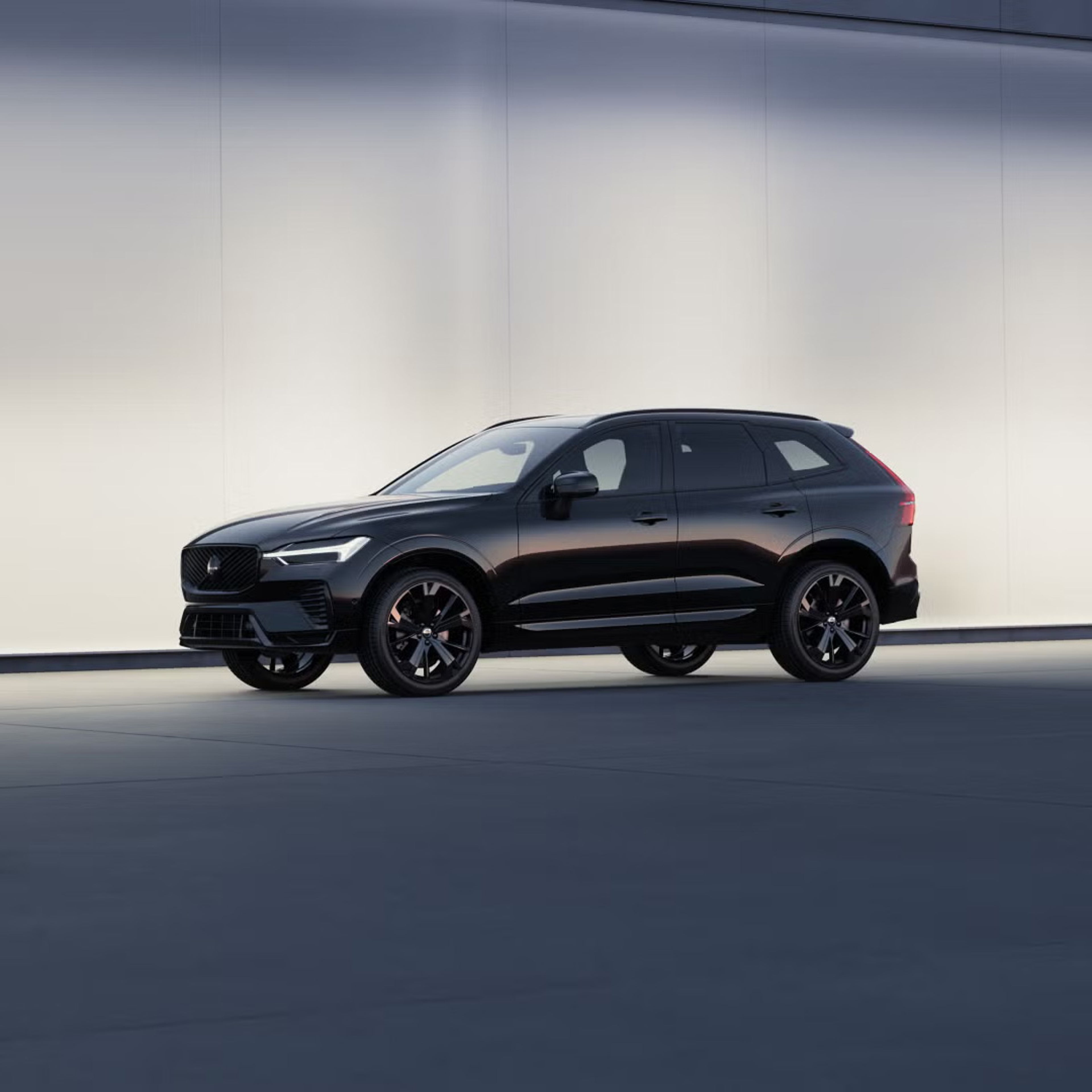 Side view of XC60 black edition parked against a softly lit wall