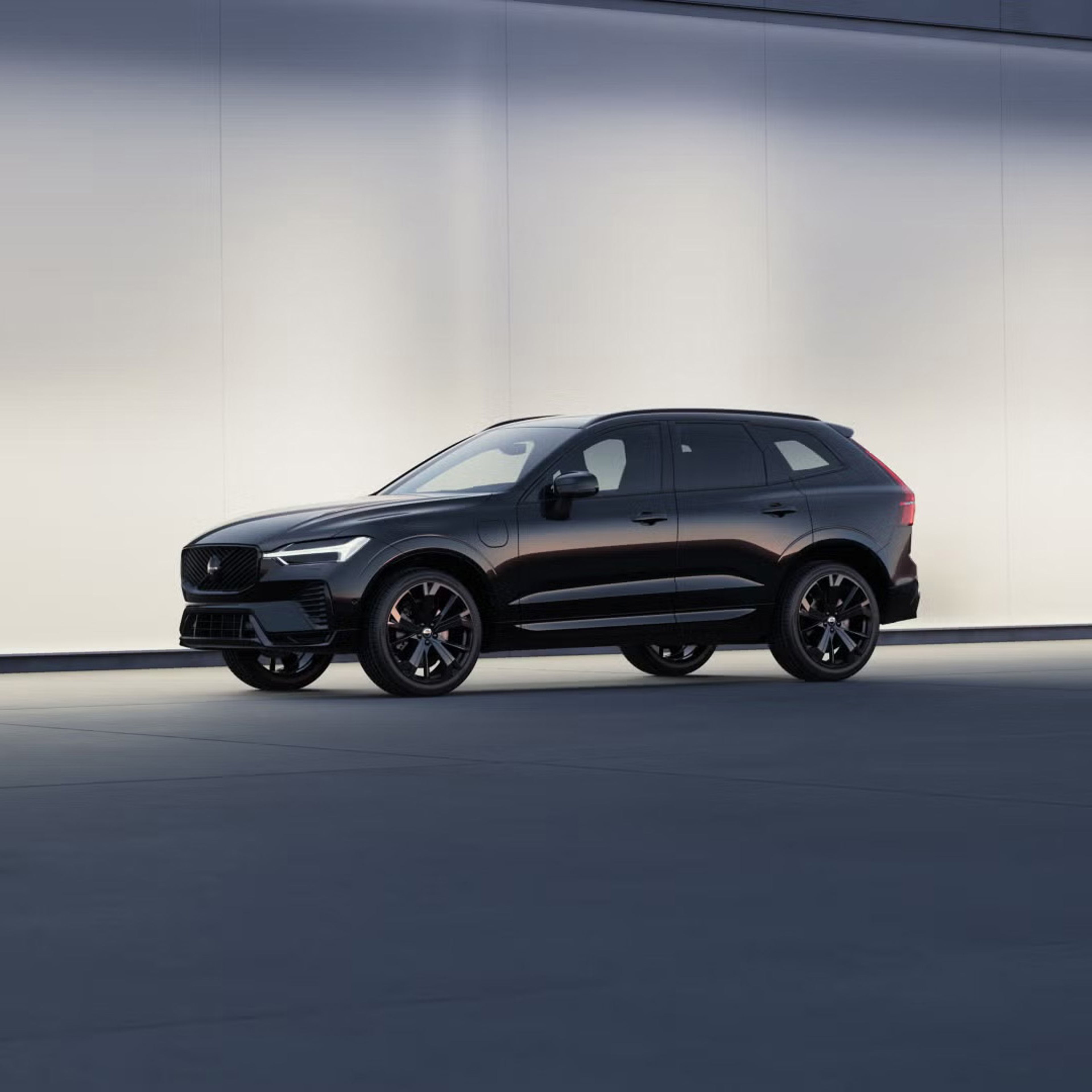 Side view of XC60 plug-in hybrid black edition against softly lit wall