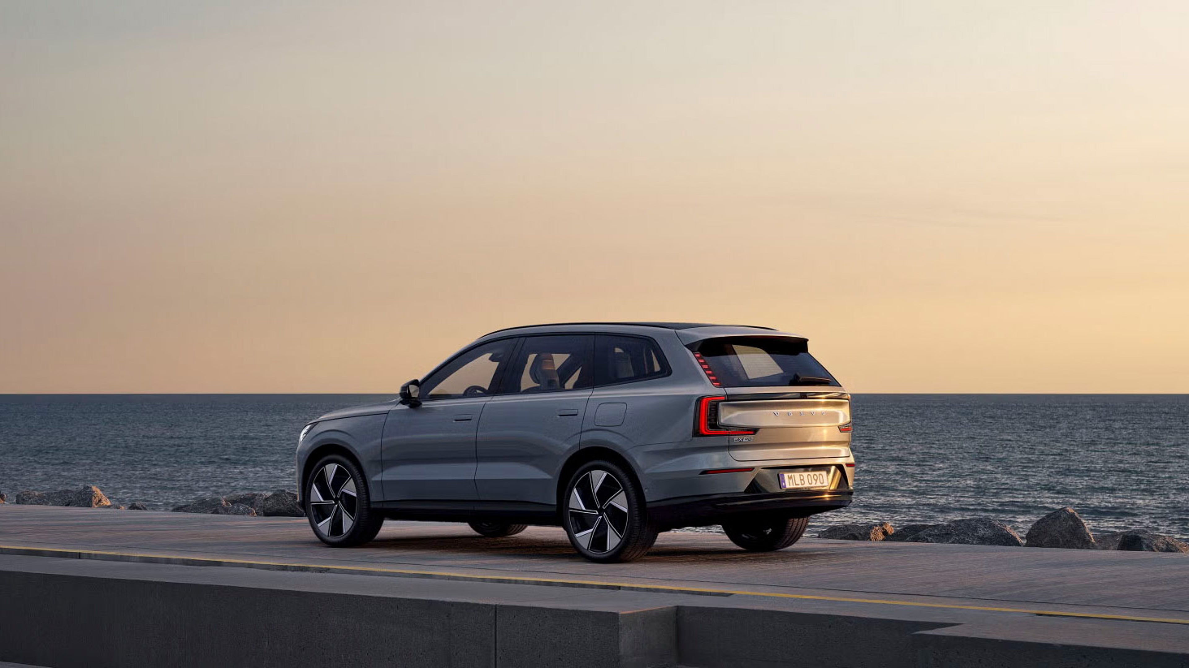 Side view of EX90 beside rocky coastline during sunrise