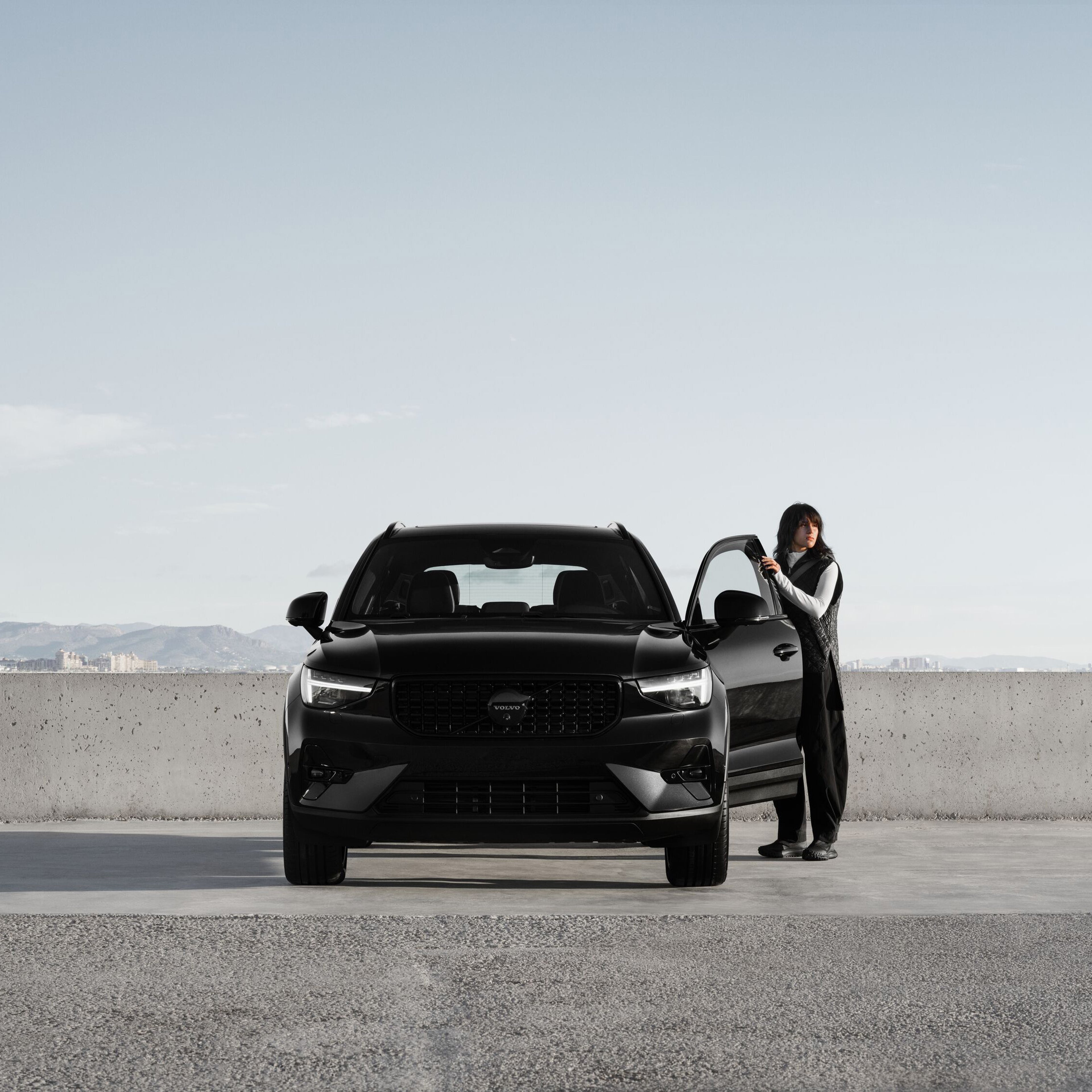 Front view of XC40 black edition with someone stood beside it with a door open
