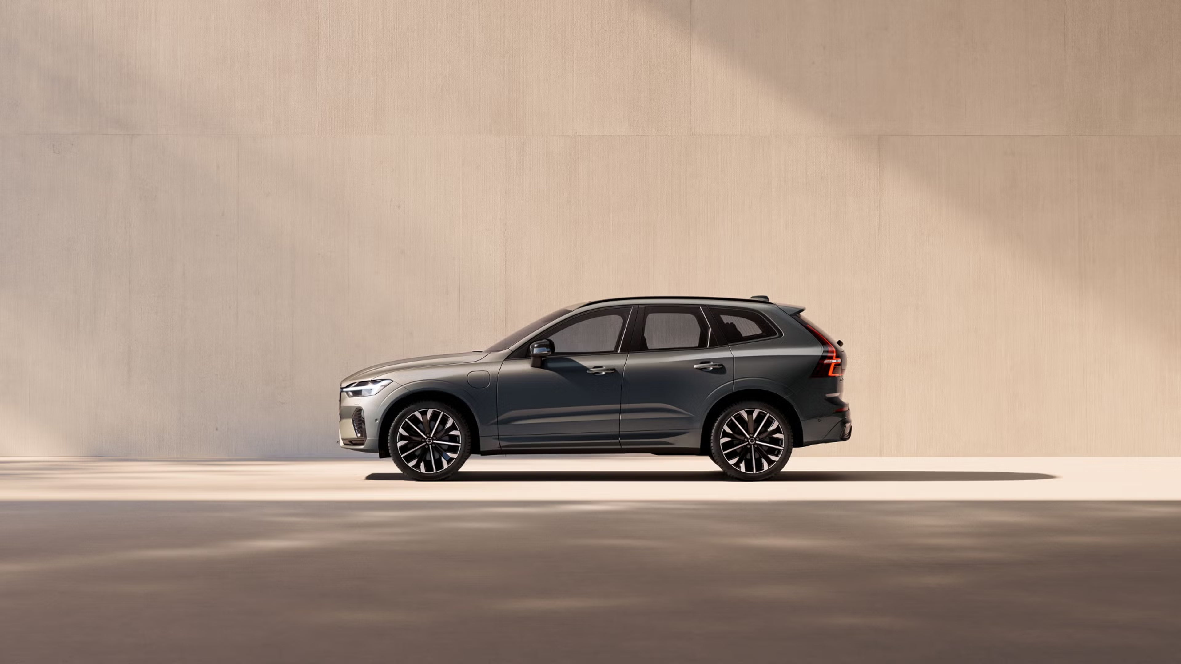 Volvo XC60 plug-in hybrid in sunlight next to concrete wall