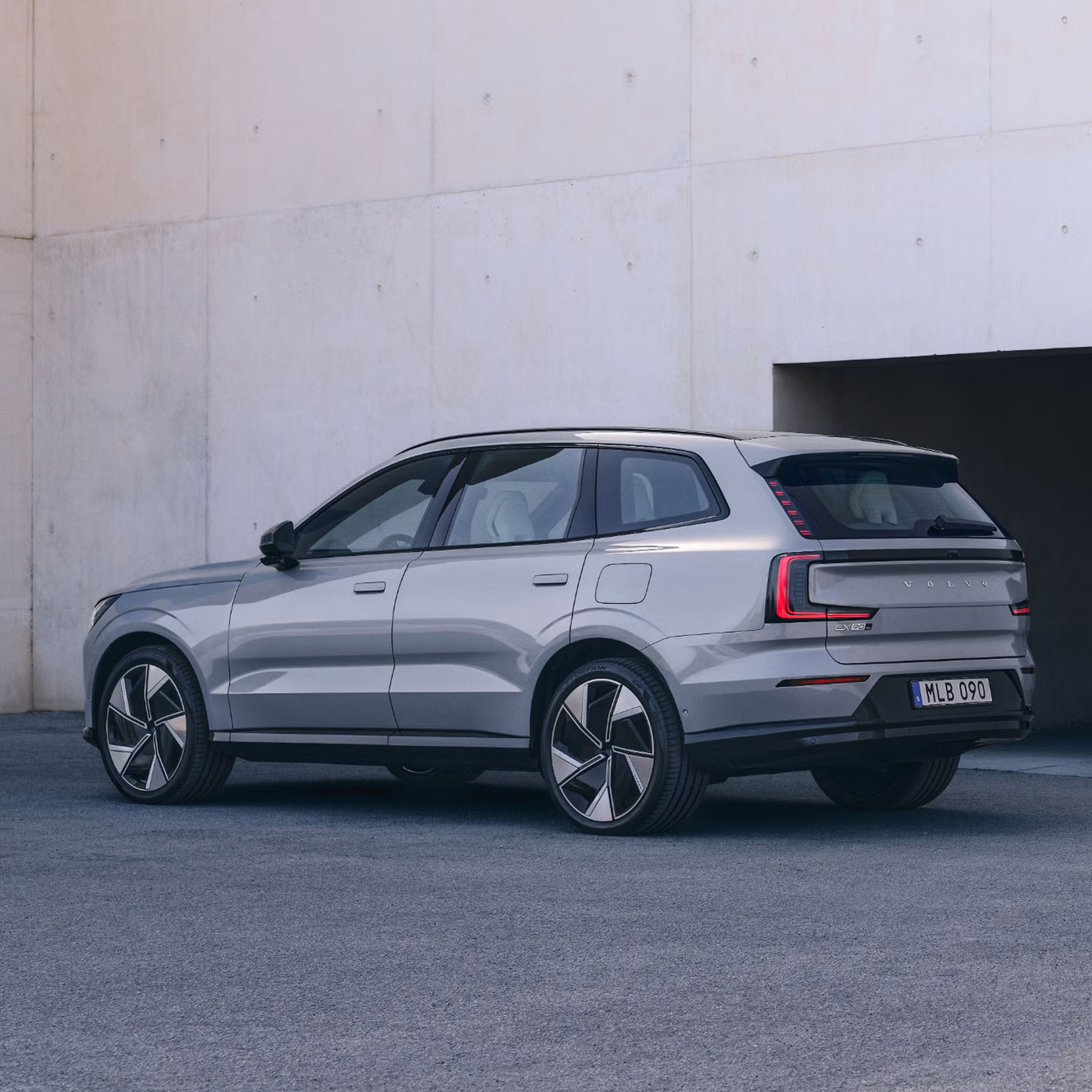 Side view of EX90 parked in front of a beige wall