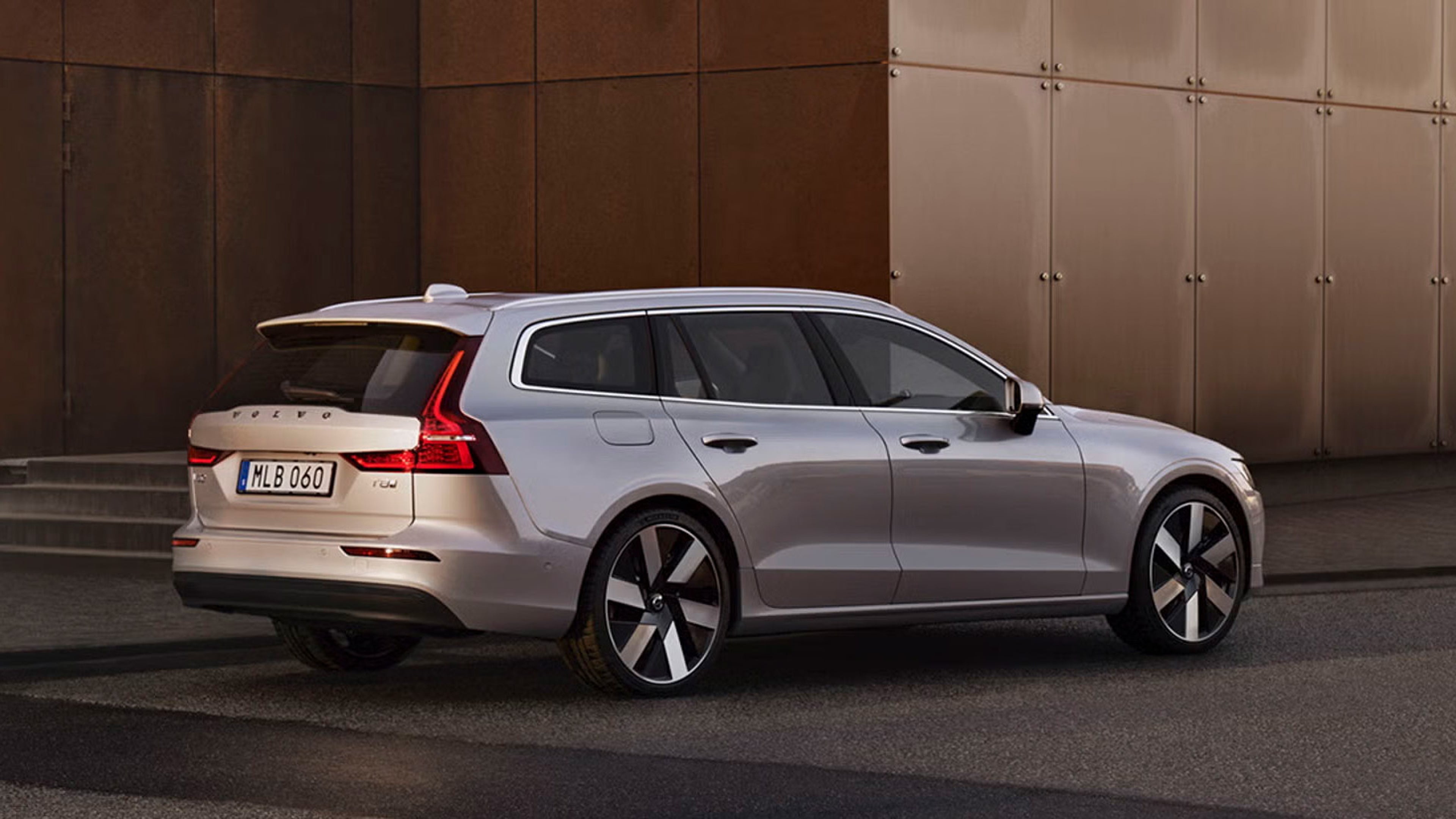 Side view of Volvo V90 plug-in hybrid in front of bronze wall